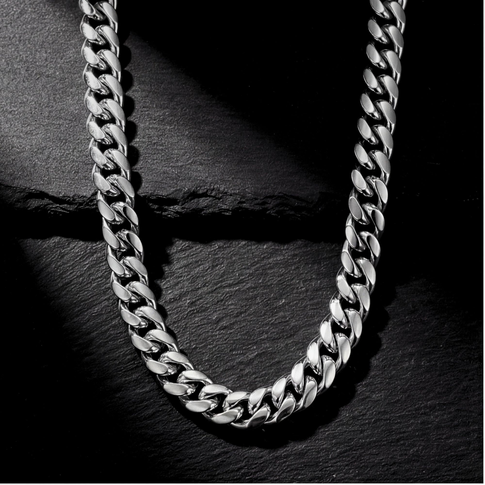 10mm silver stainless steel Cuban link chain displayed on a dark textured stone background.
