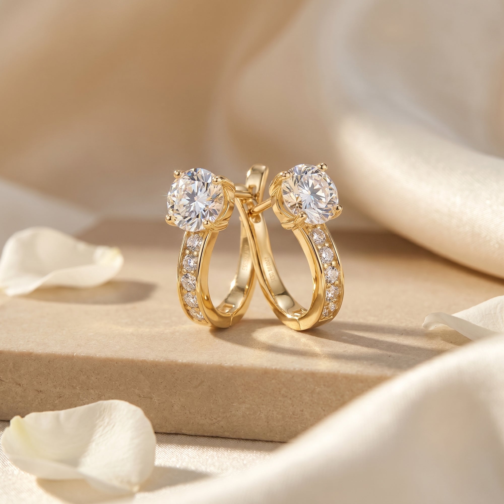 Gold moissanite hoop earrings with round cut stones on a silk lifestyle background.