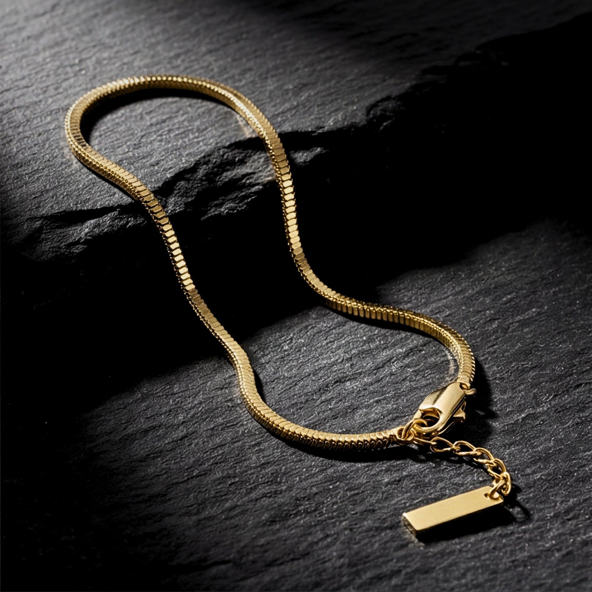 Gold-tone stainless steel square link bracelet for men laid out on a dark, textured slate surface.
