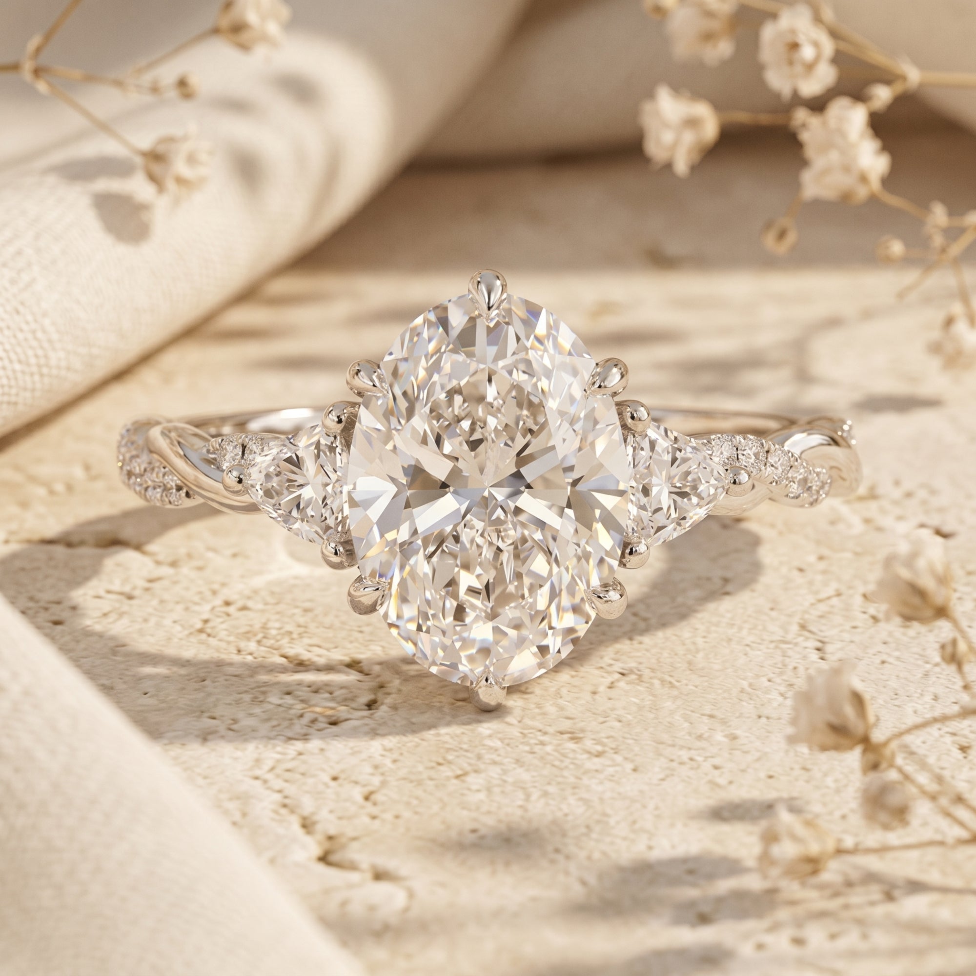 3-carat oval moissanite ring in sterling silver on a textured surface with dried flowers.