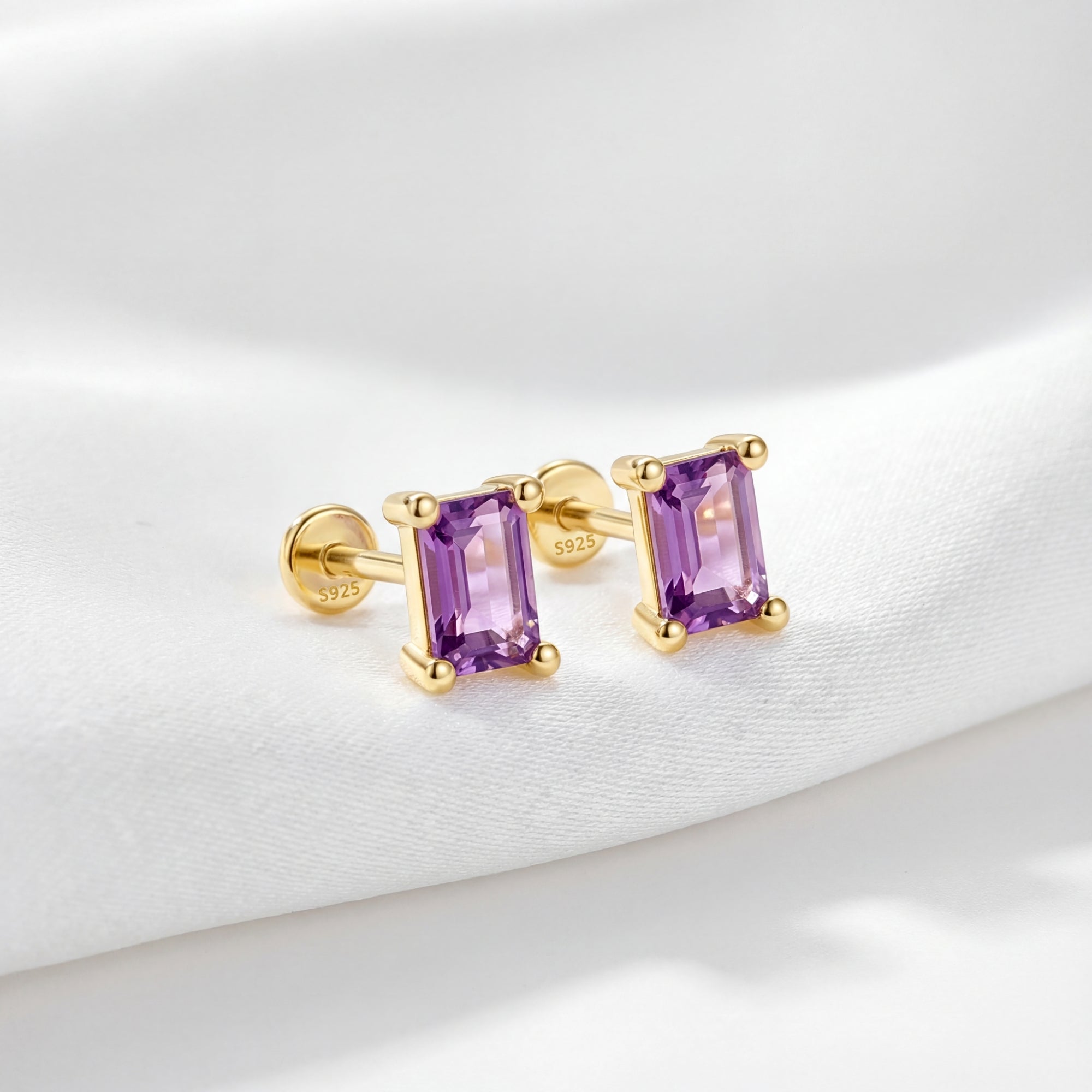 Emerald cut simulated amethyst stud earrings in 18K gold vermeil on white fabric showing the S925 hallmark.