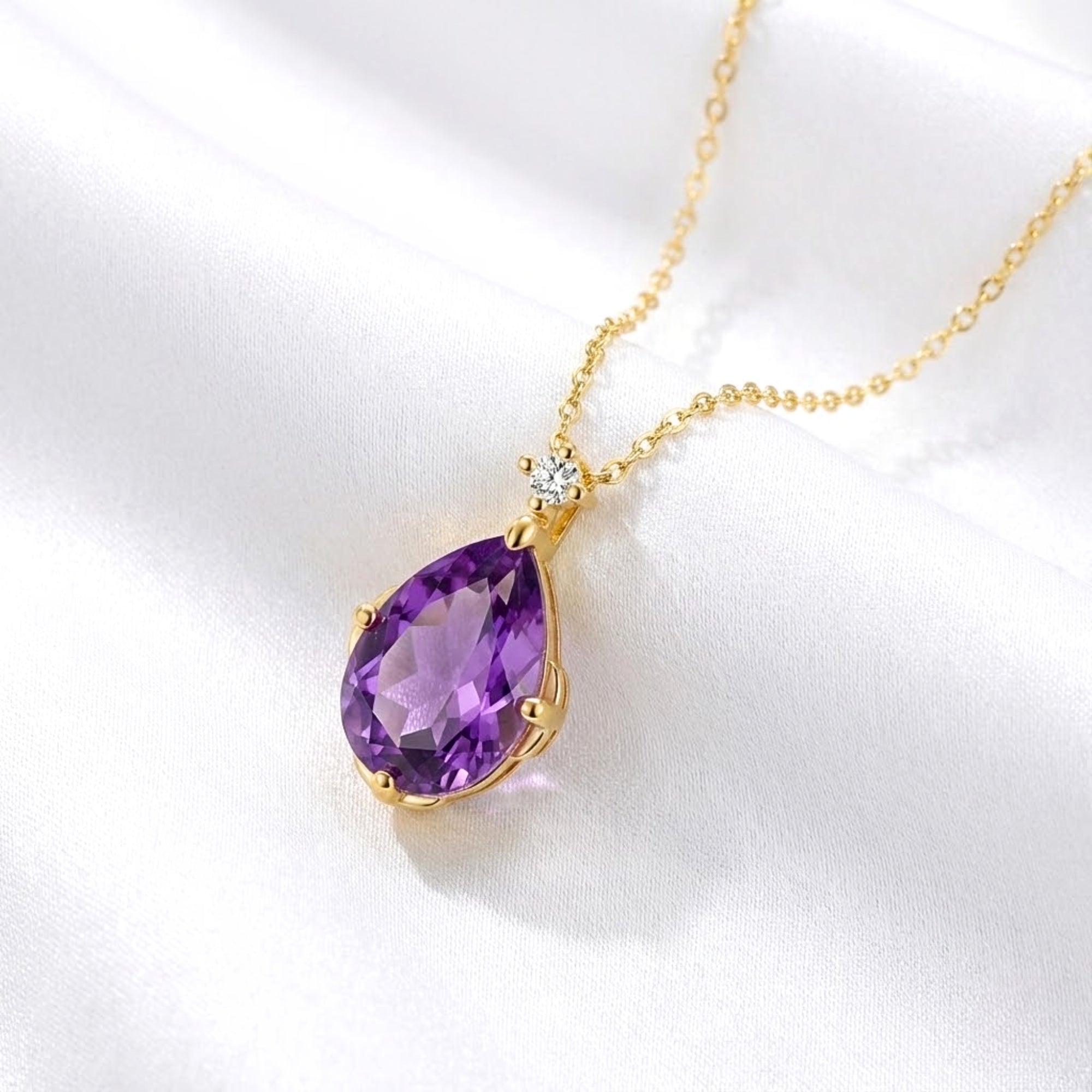 Pear-cut simulated amethyst teardrop necklace in 18K gold vermeil resting on white silk fabric.