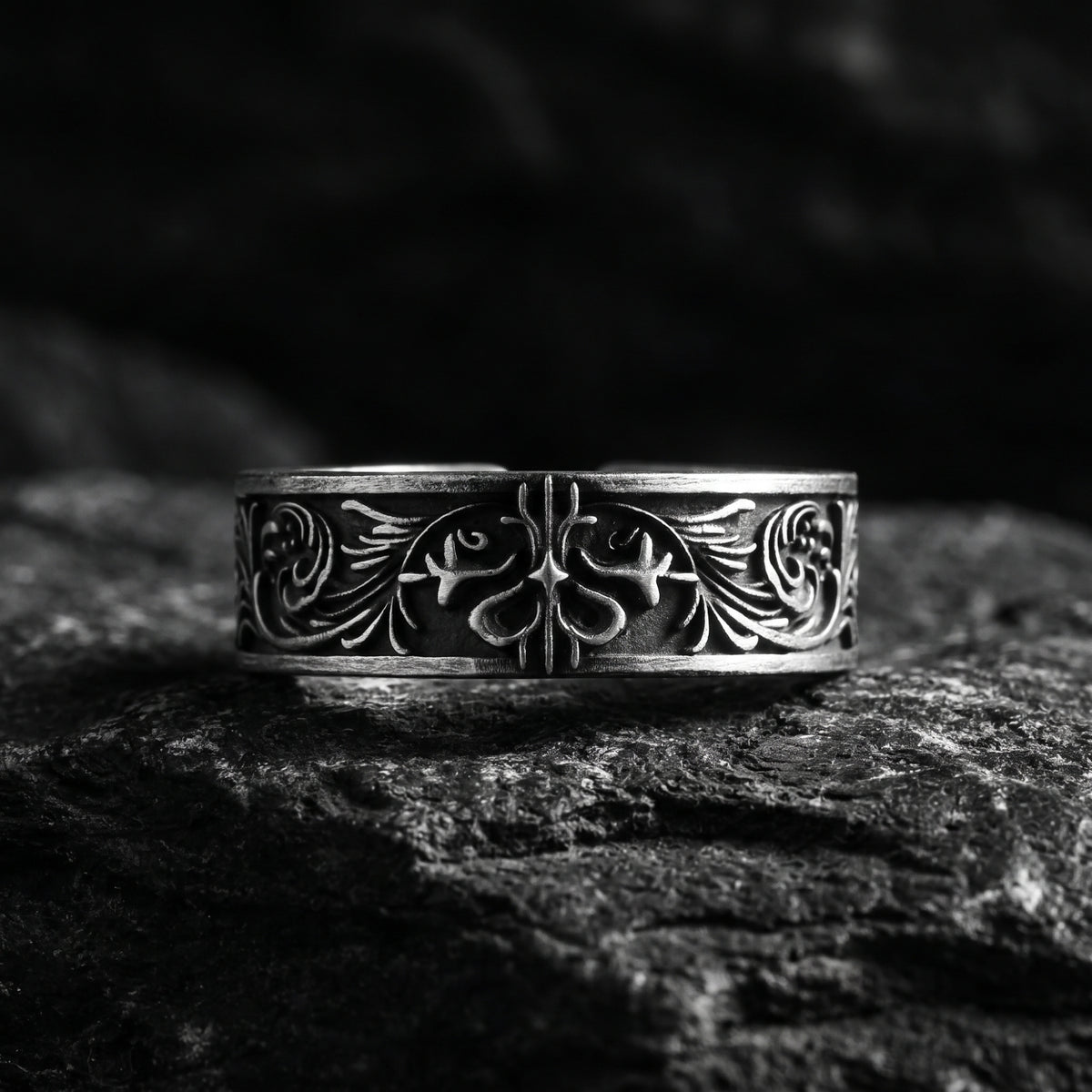 Front view of the silver filigree band ring with oxidized scrollwork on a dark textured surface.