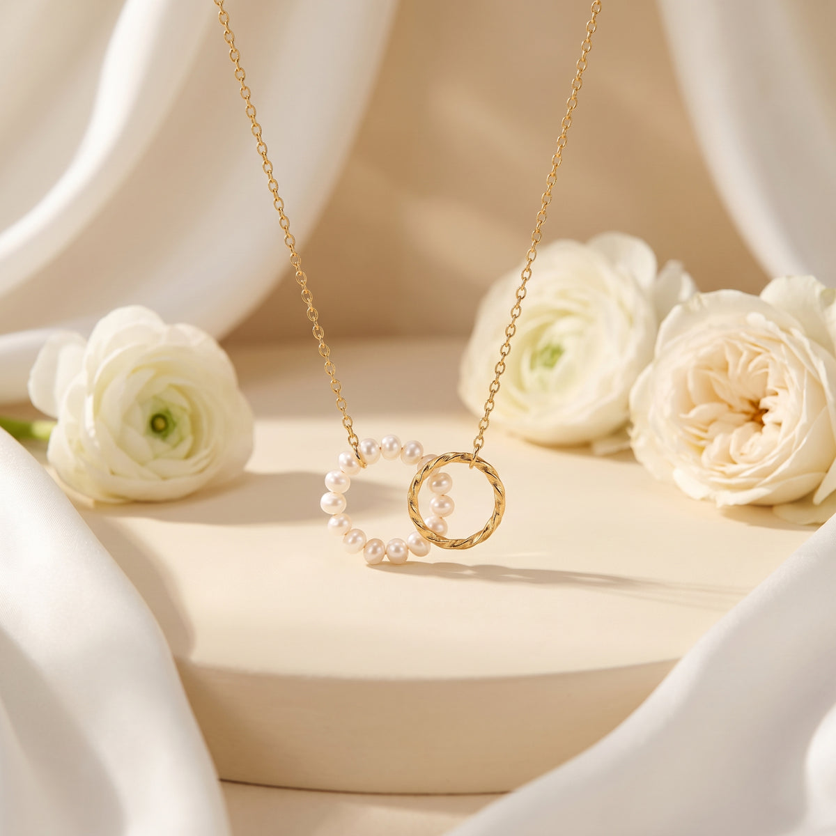 Gold-tone necklace with a pearl circle and twisted interlocking ring, displayed among white flowers.