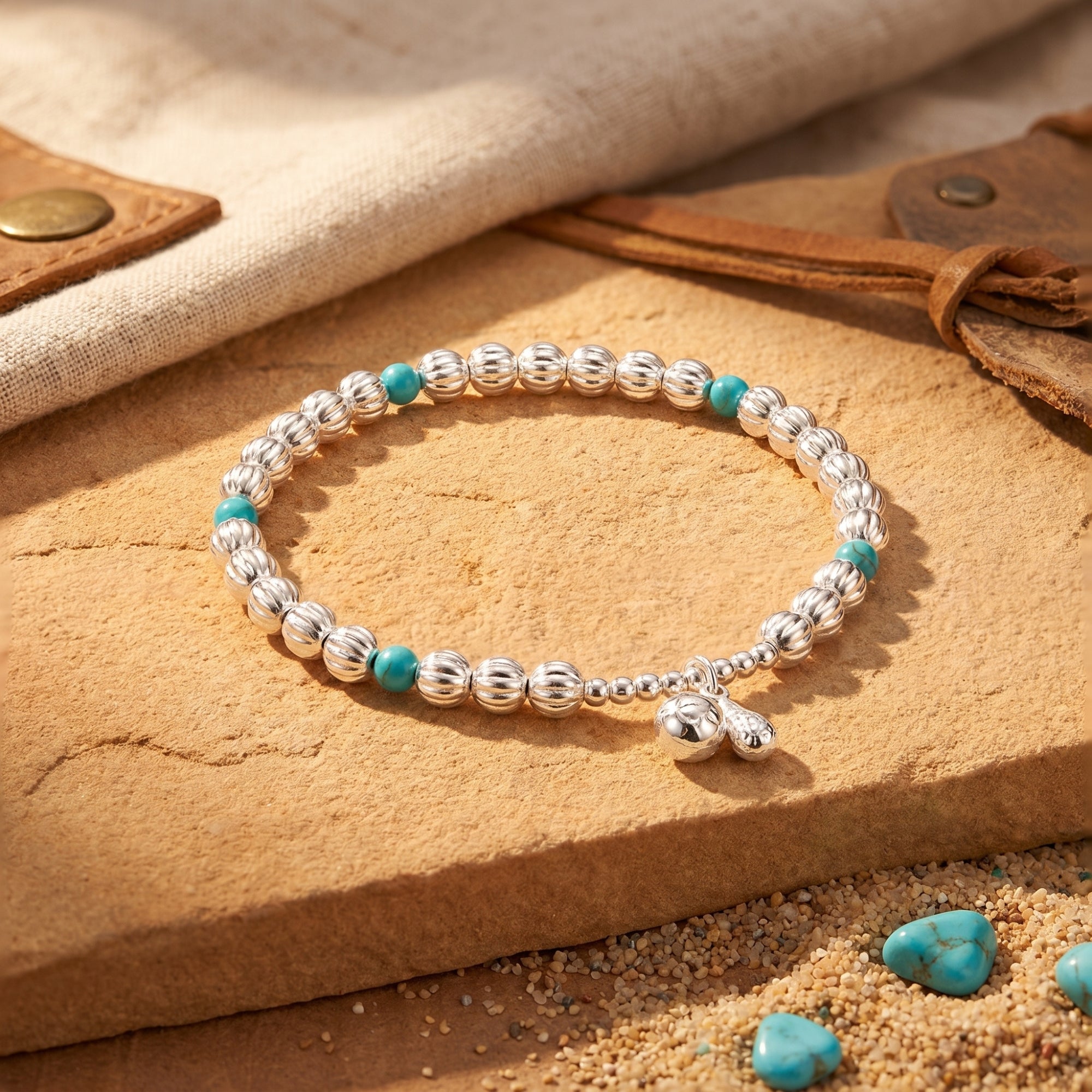 Sterling silver Navajo-style bead bracelet with turquoise accents on a desert stone surface.