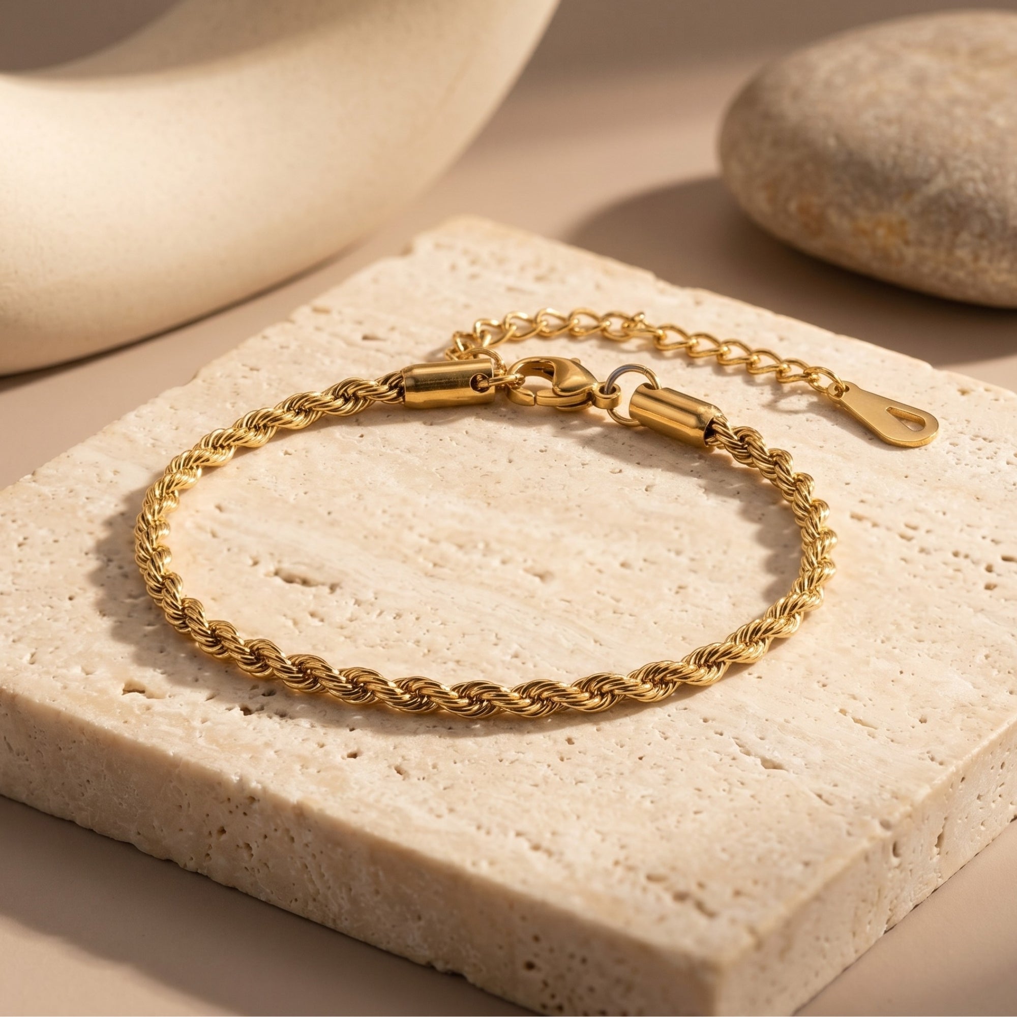 Gold 18K plated stainless steel rope bracelet on a stone slab lifestyle background.