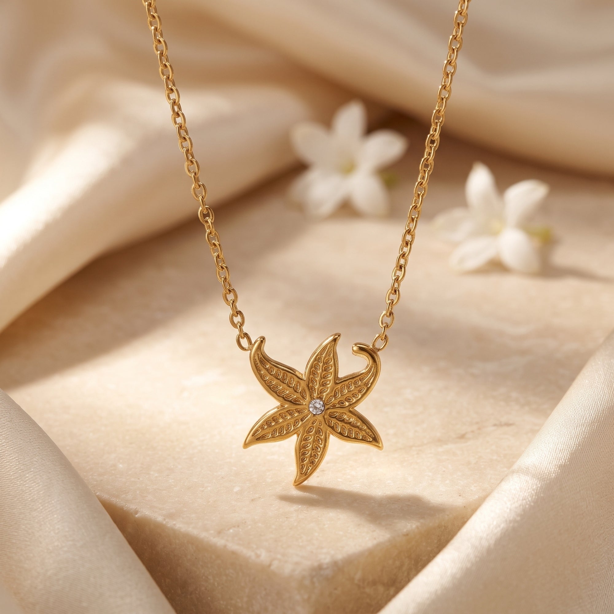 Gold starfish pendant necklace with a round center stone on a neutral lifestyle background.
