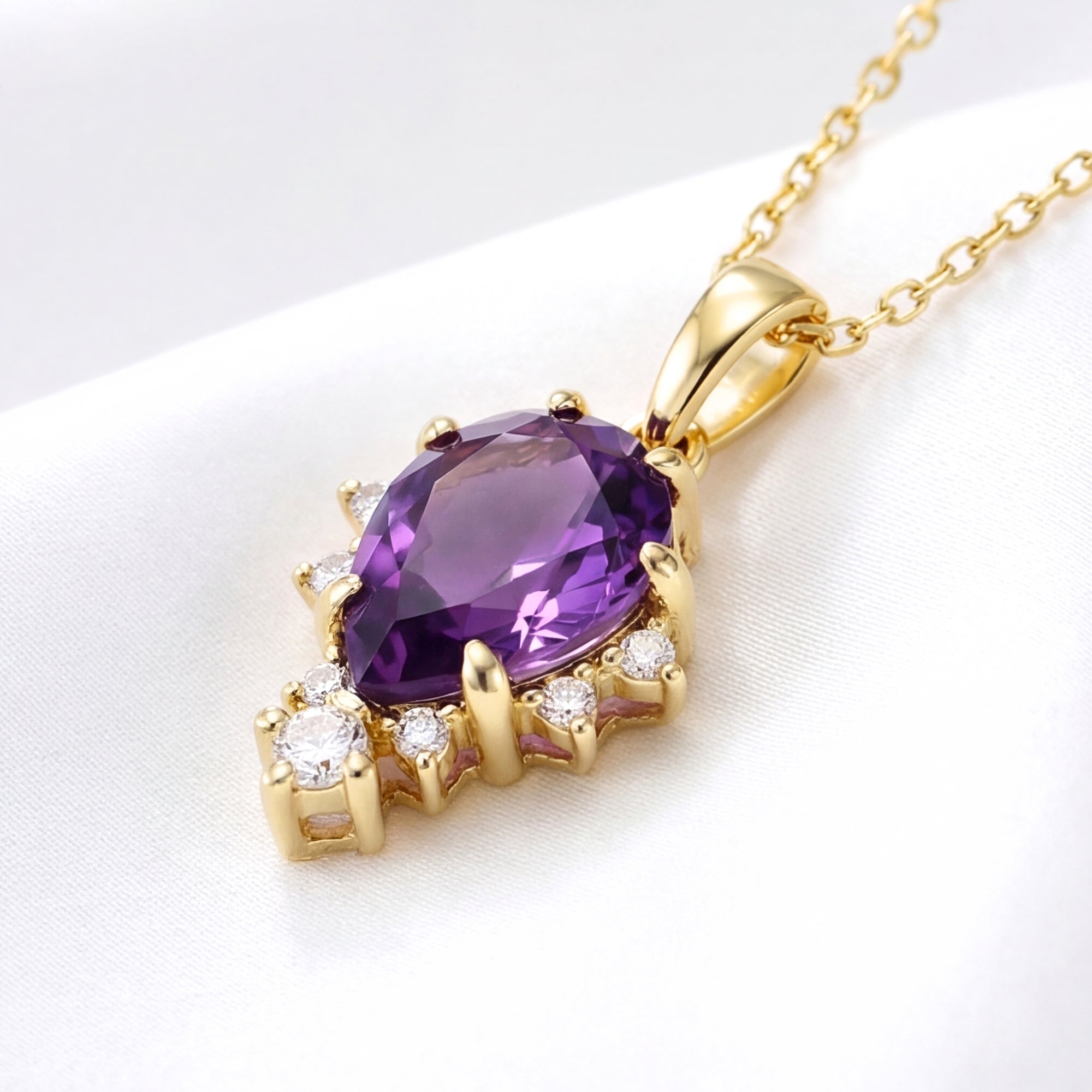 Angled close-up of the pear cut simulated amethyst pendant in 18K gold vermeil on white silk.