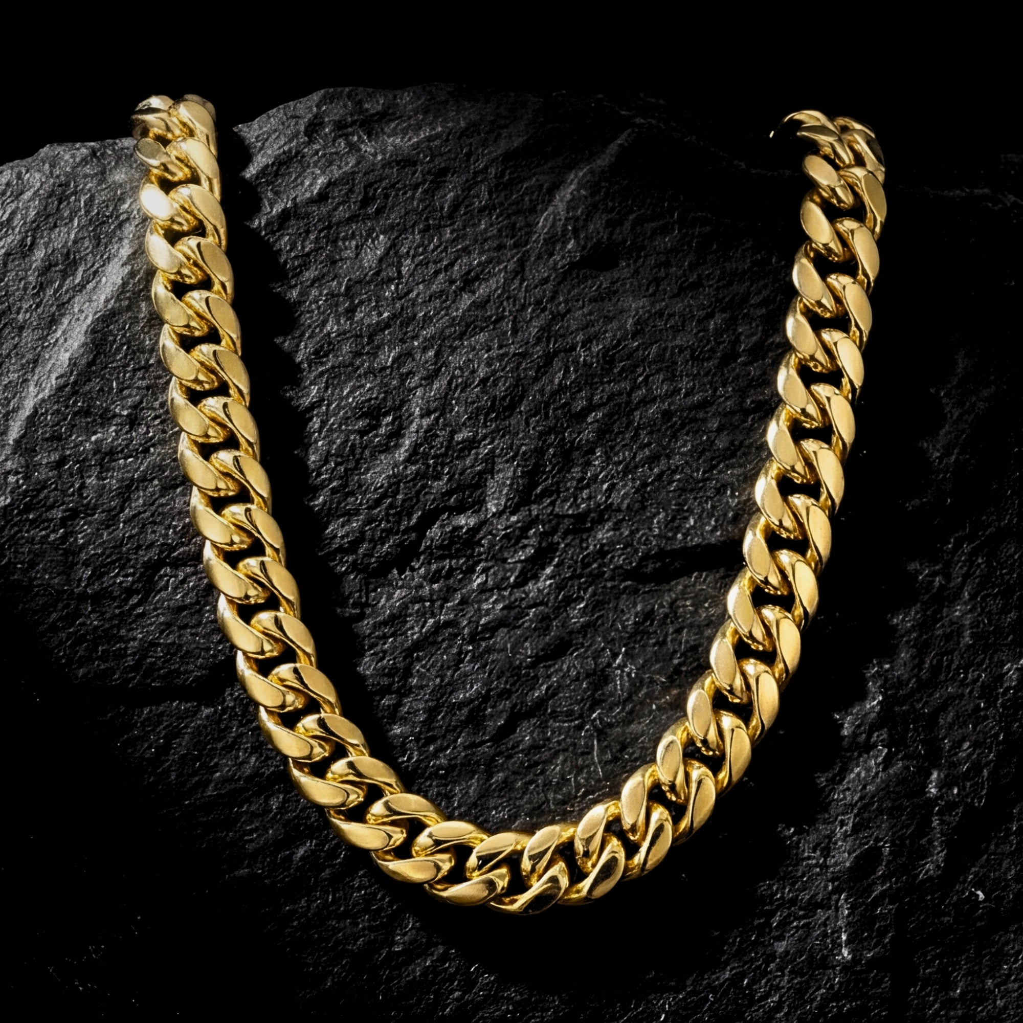 10mm gold Cuban link chain for men made of stainless steel draped over a dark textured rock.