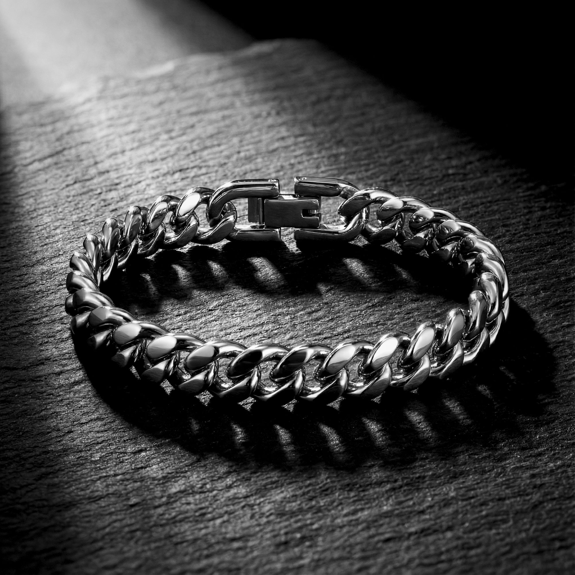 Silver stainless steel 8mm Cuban link bracelet lying flat on a dark textured stone background.