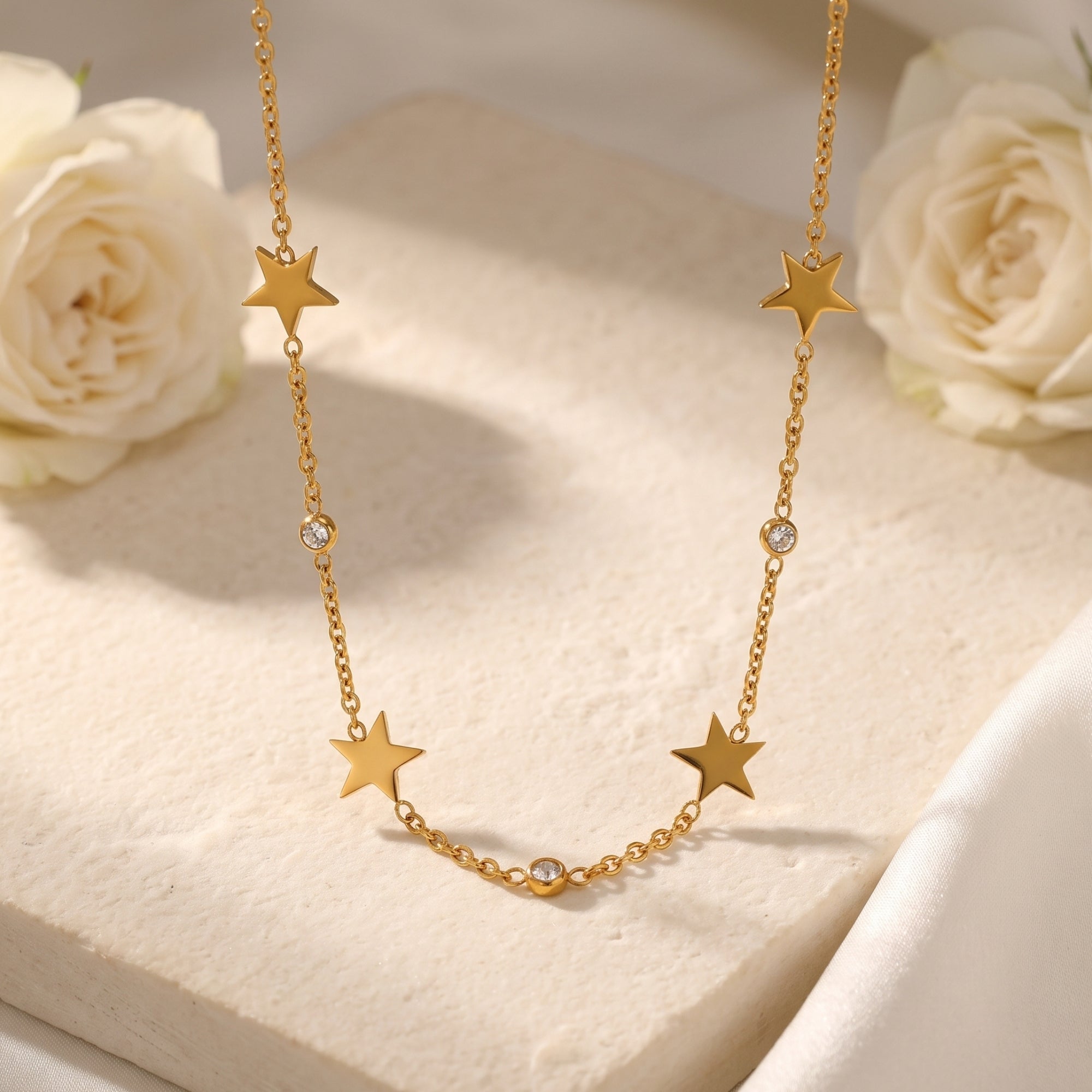 18K gold star charm necklace with round simulated diamonds on a stone block with white roses.