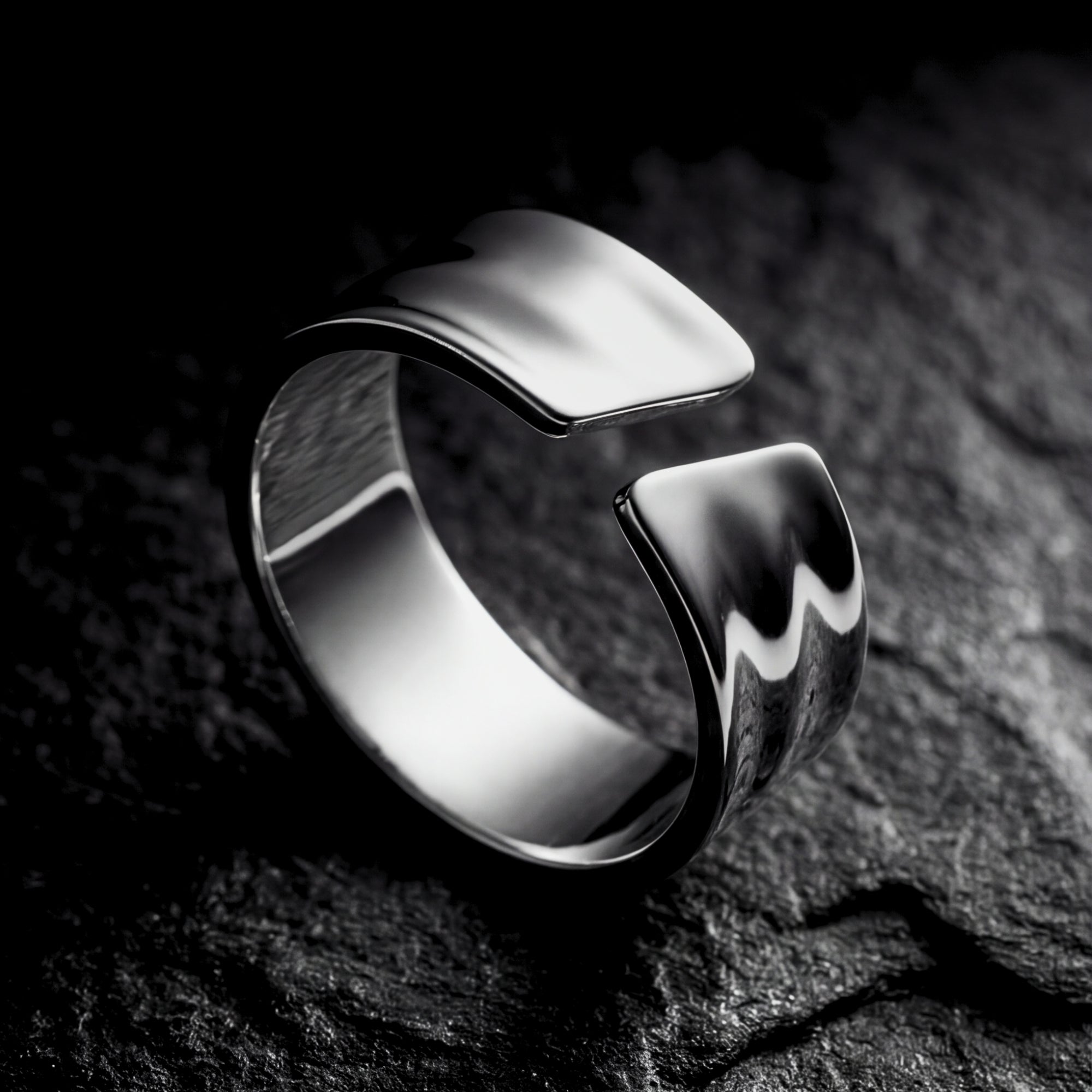 Polished silver stainless steel Origin Flex adjustable ring on a dark textured stone background.