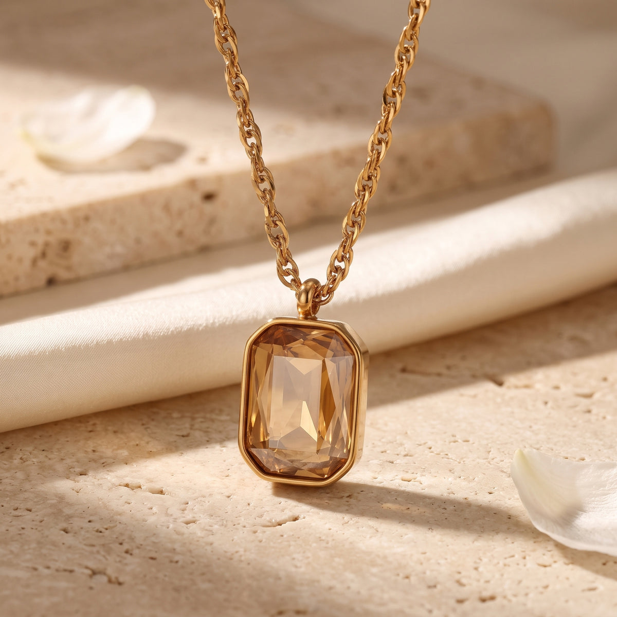 Close-up of a gold-tone necklace with an emerald-cut golden-yellow simulated citrine pendant in a bezel setting.