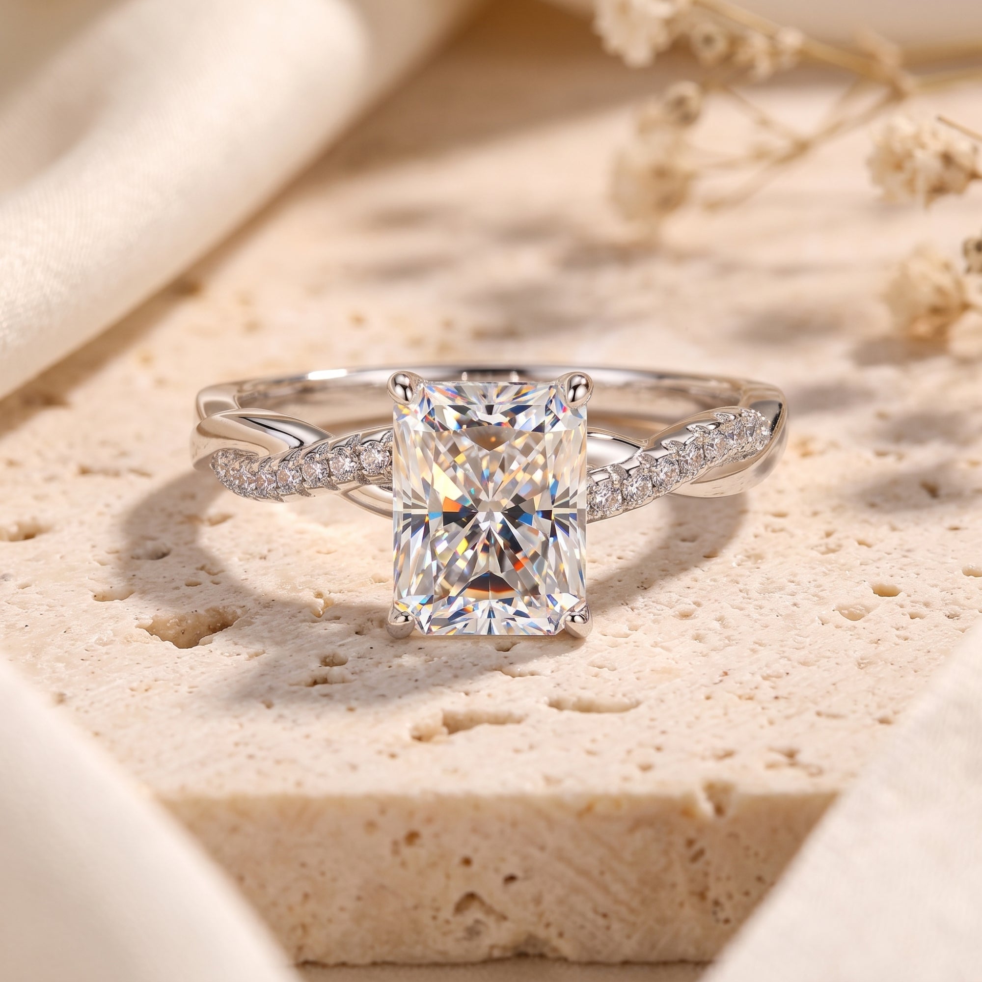 Radiant cut simulated diamond ring in sterling silver with twisted pavé band on textured stone.