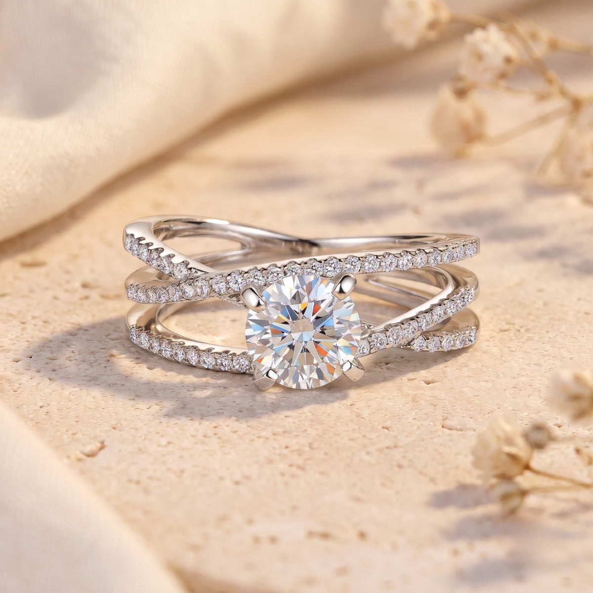Silver criss-cross promise ring with round center stone on a textured surface with floral accents.