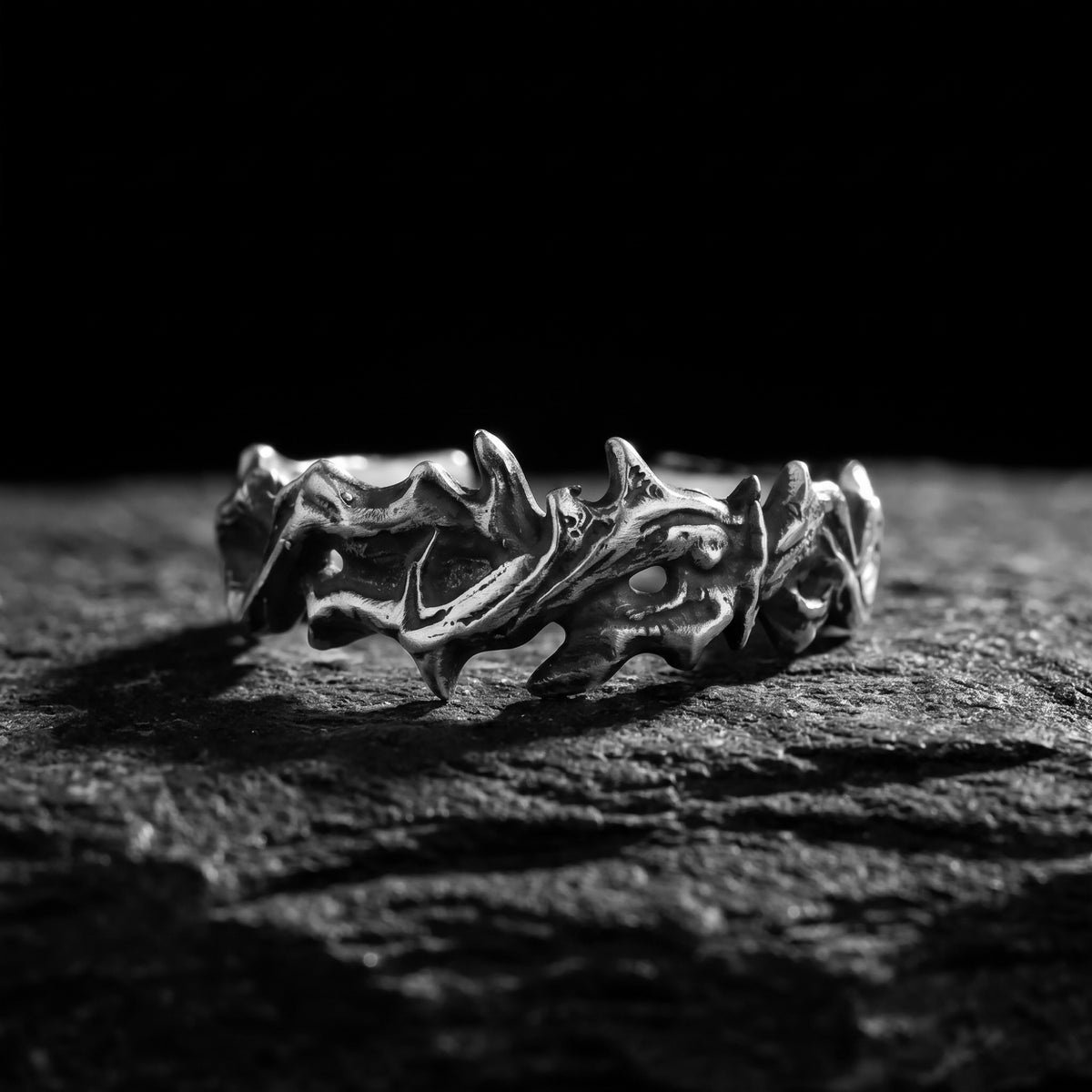 Front macro view of the oxidized silver thorn open band ring resting on a dark stone surface.