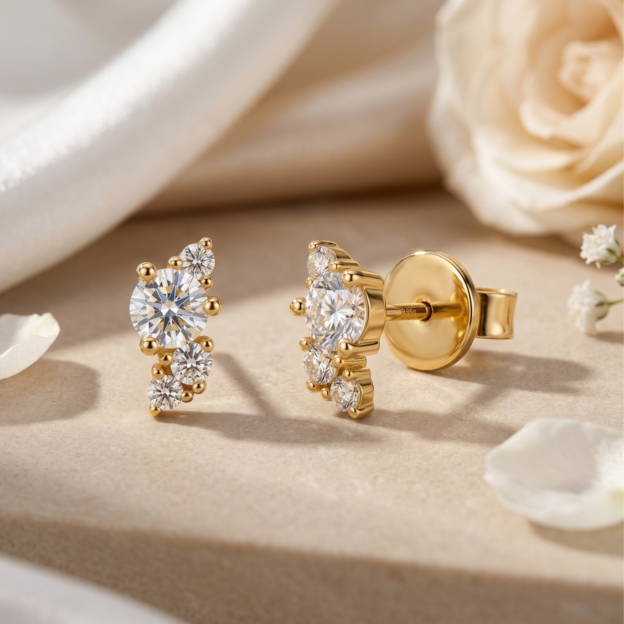 Gold moissanite cluster earrings with round stones on a neutral surface with roses.