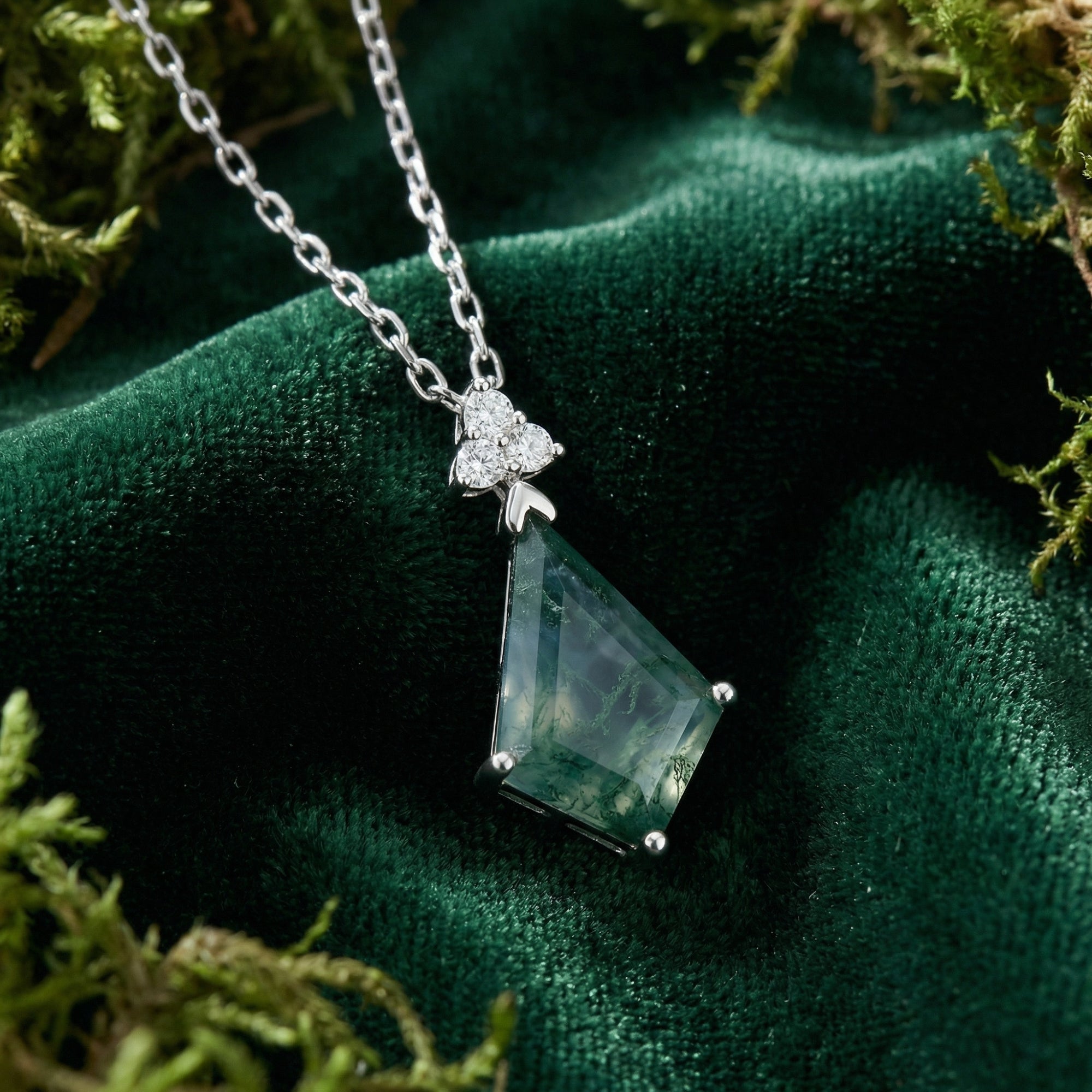 Kite cut moss agate necklace in sterling silver resting on green velvet and natural moss.