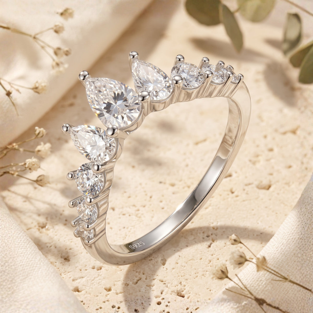 Macro view of a silver tiara ring with pear and round clear stones, stamped S925 on the inner band.