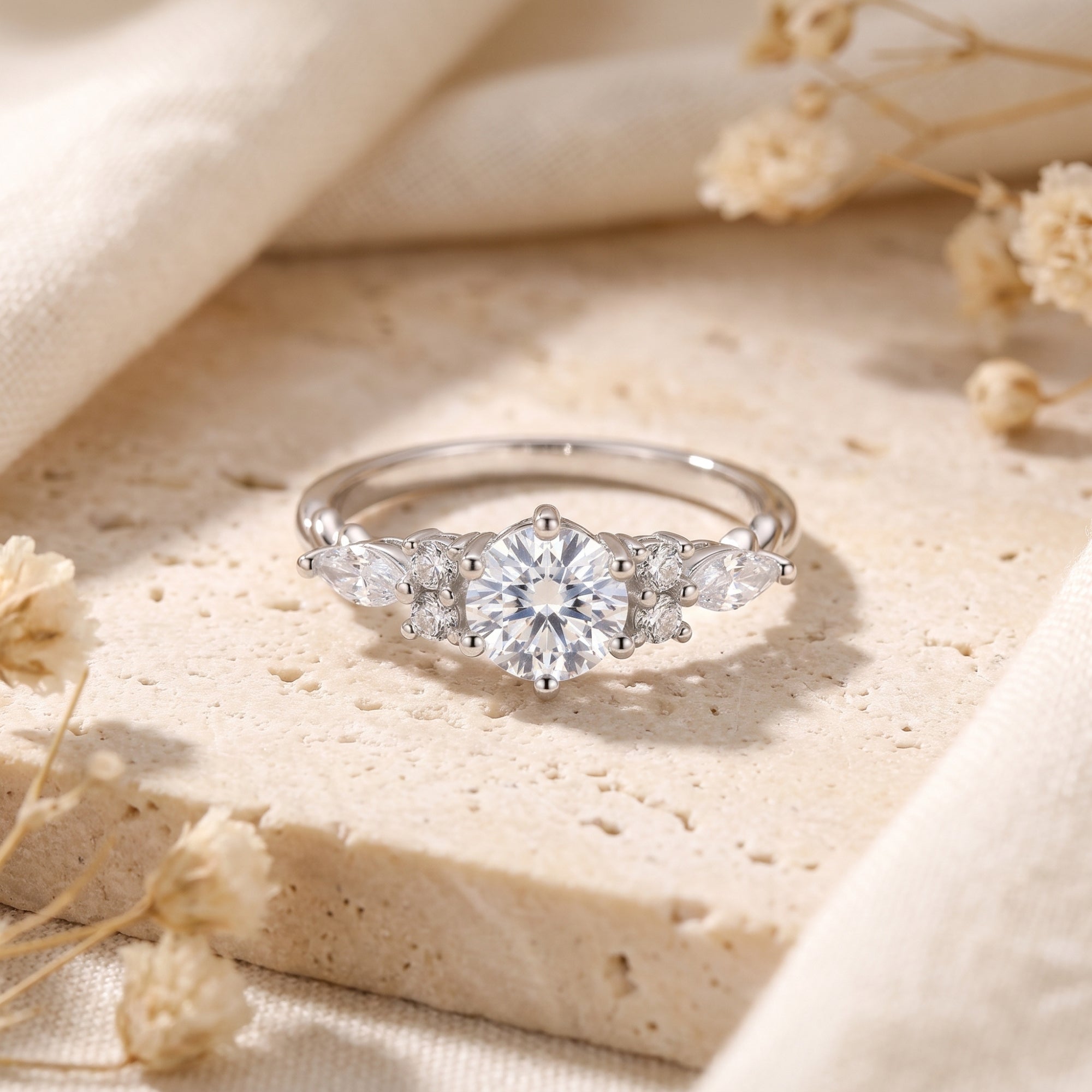 Sterling silver Claraluna ring with round and marquise simulated diamonds on a stone surface.