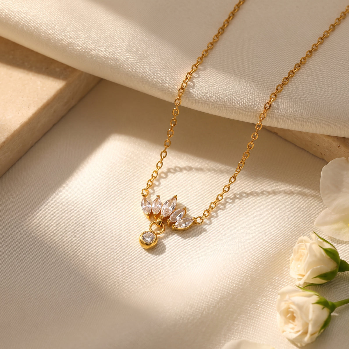 Gold-tone lotus cluster necklace with marquise CZ stones displayed flat on cream fabric.