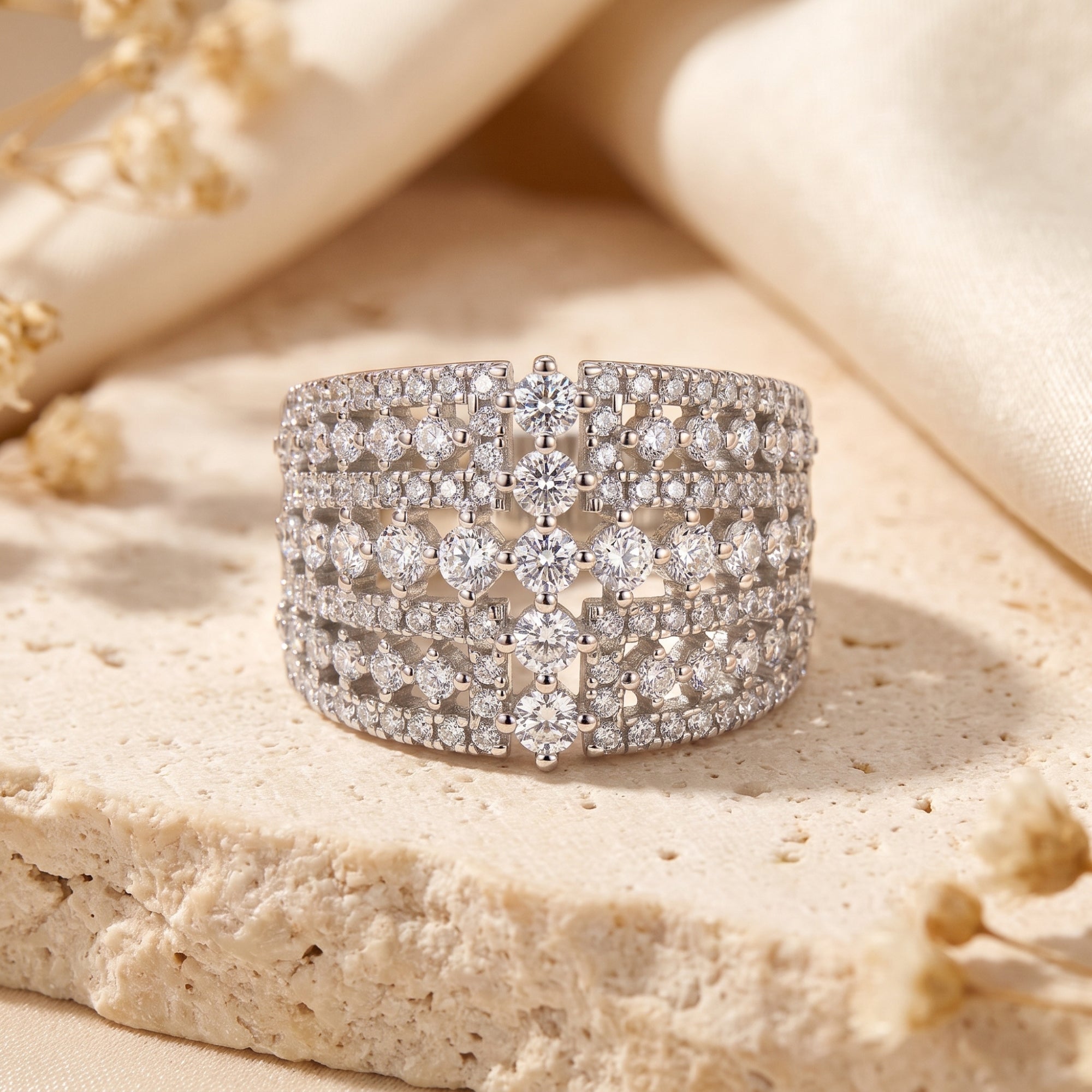 Eleonora sterling silver statement band with round simulated diamonds on a textured stone surface.