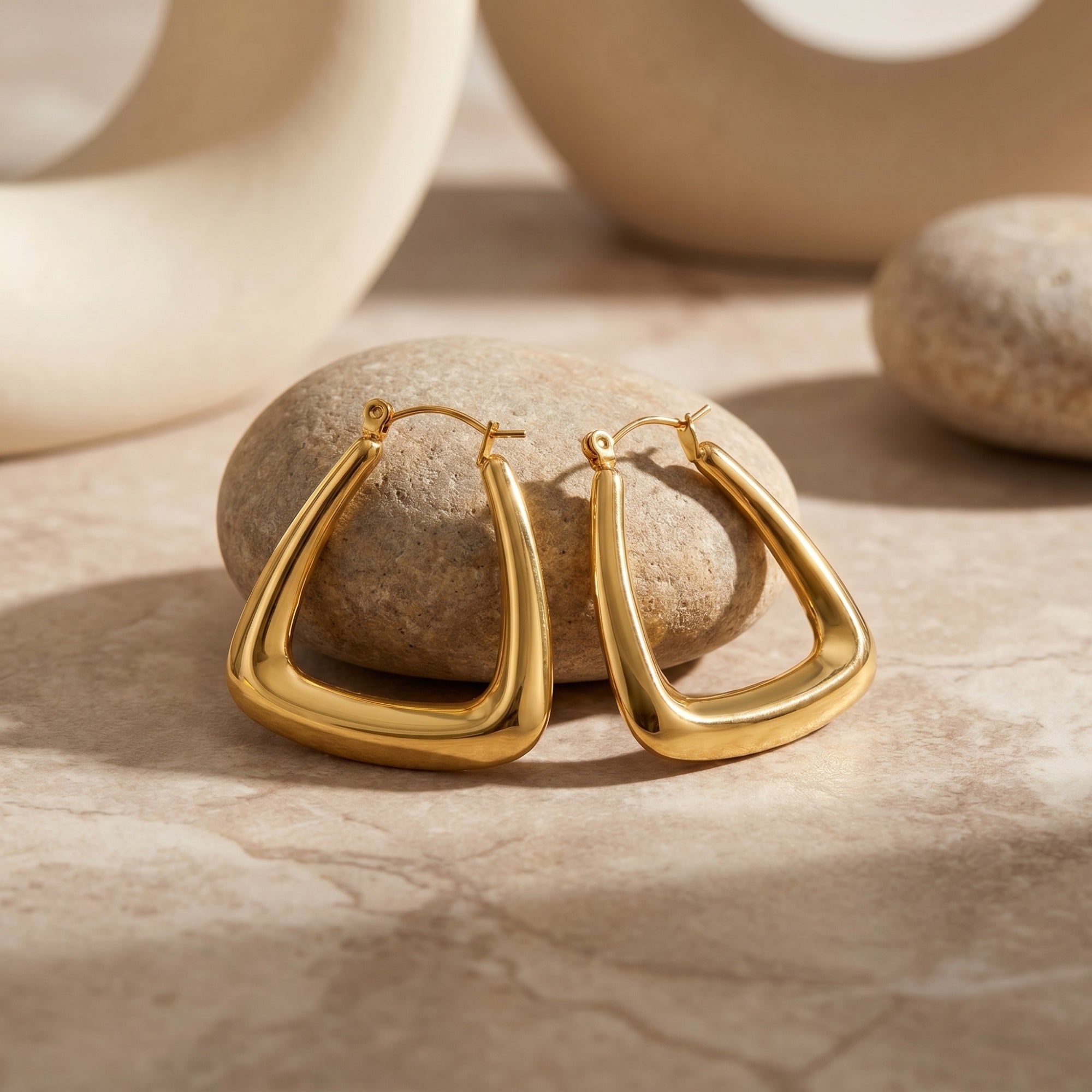 Gold 18K PVD stainless steel triangle hoops on a stone.