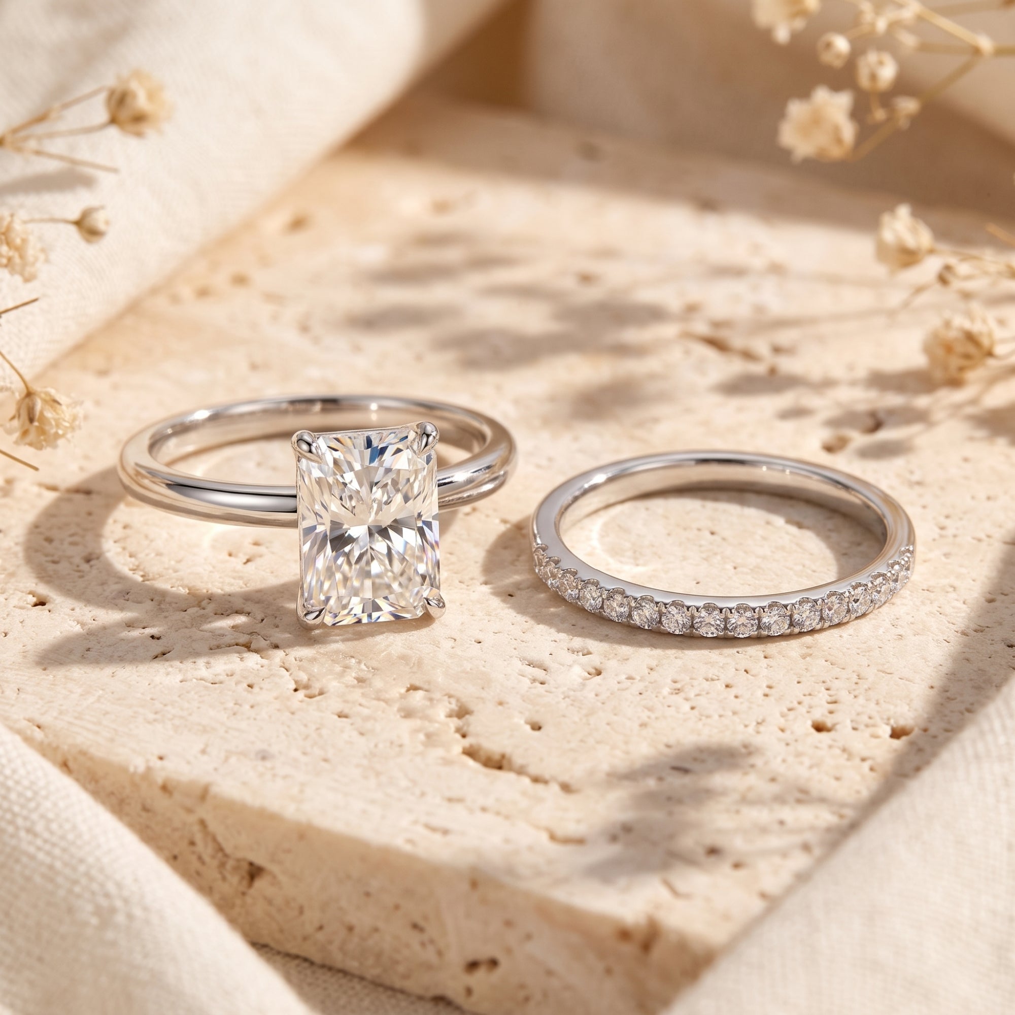 Emerald-cut simulated diamond ring and pavé band in S925 sterling silver on a stone surface.
