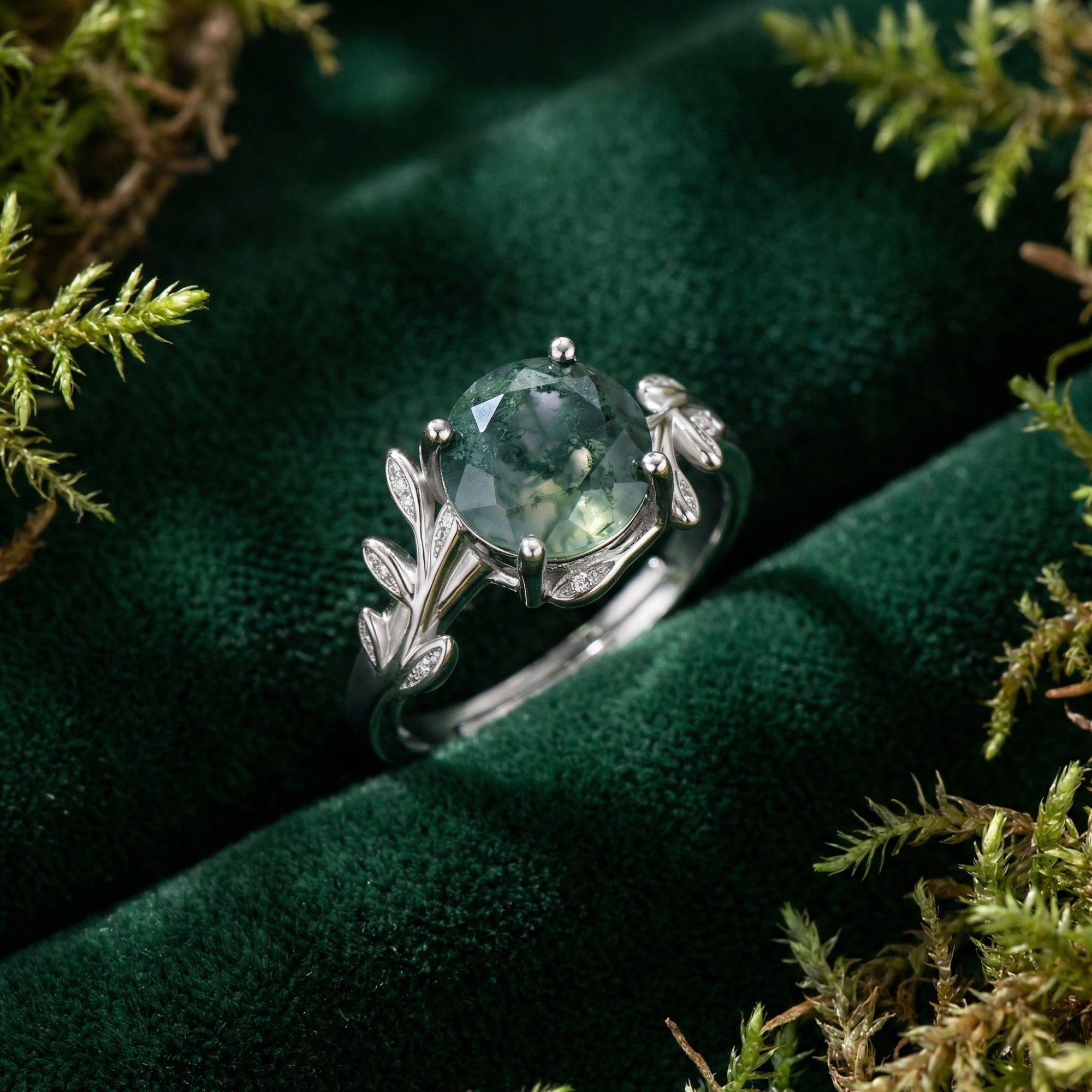 Silver S925 floral crest ring with a faceted round moss agate stone on green velvet with natural moss.