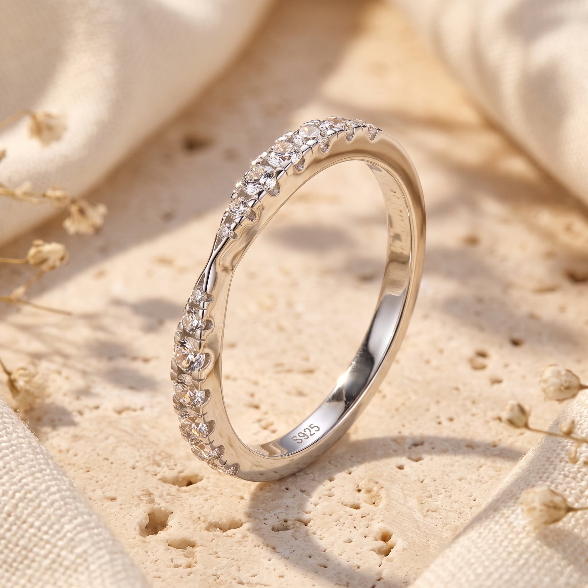 S925 sterling silver wave promise ring with round simulated diamonds on a stone surface with dried flowers.