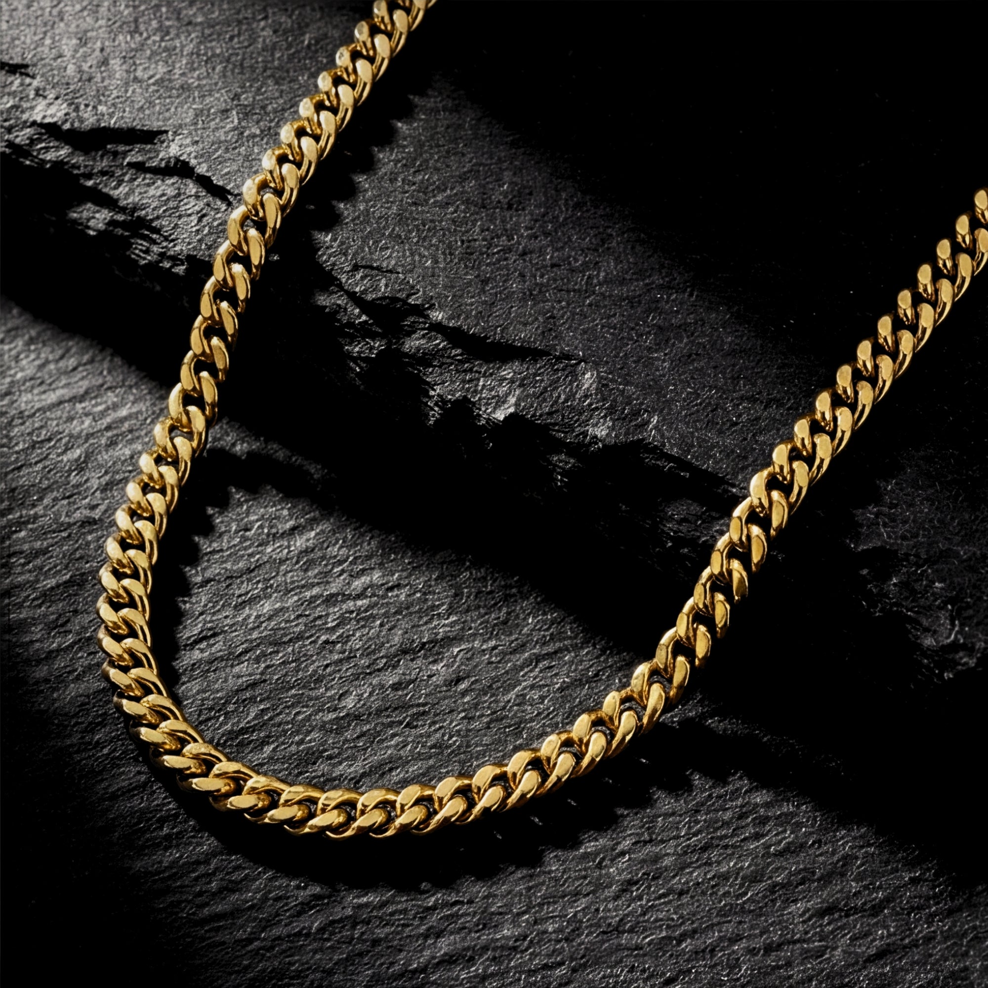 4mm gold Miami Cuban link chain in stainless steel resting on a dark textured stone surface.