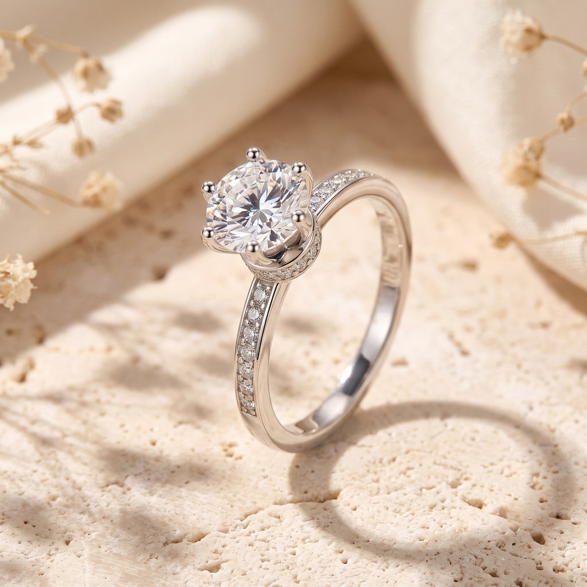 Angled close-up of a silver ring with a round clear center stone in a six-prong crown setting and pavé shoulders.