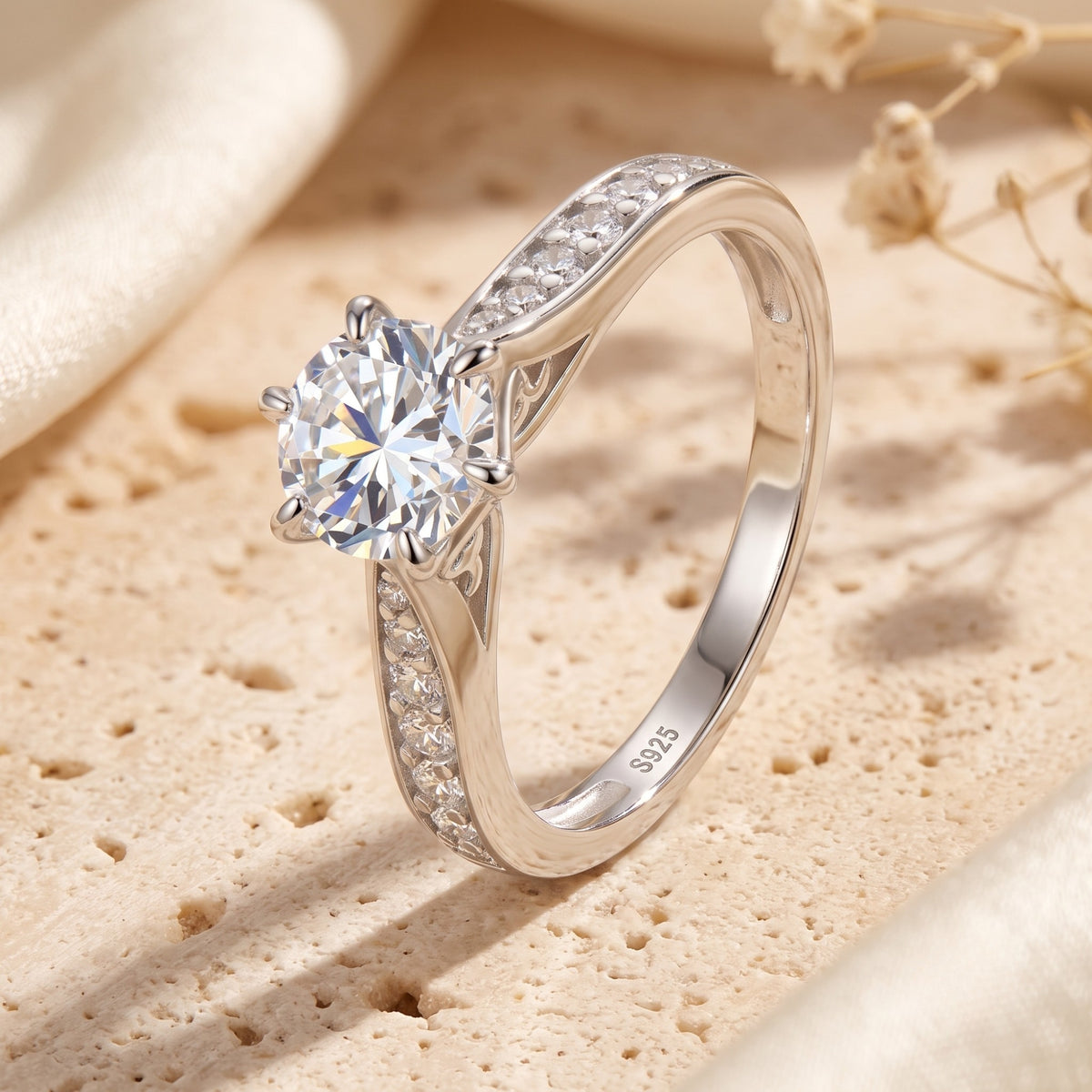 Angled side view of a silver ring with a round clear center stone, six-prong setting, and pavé accent band.