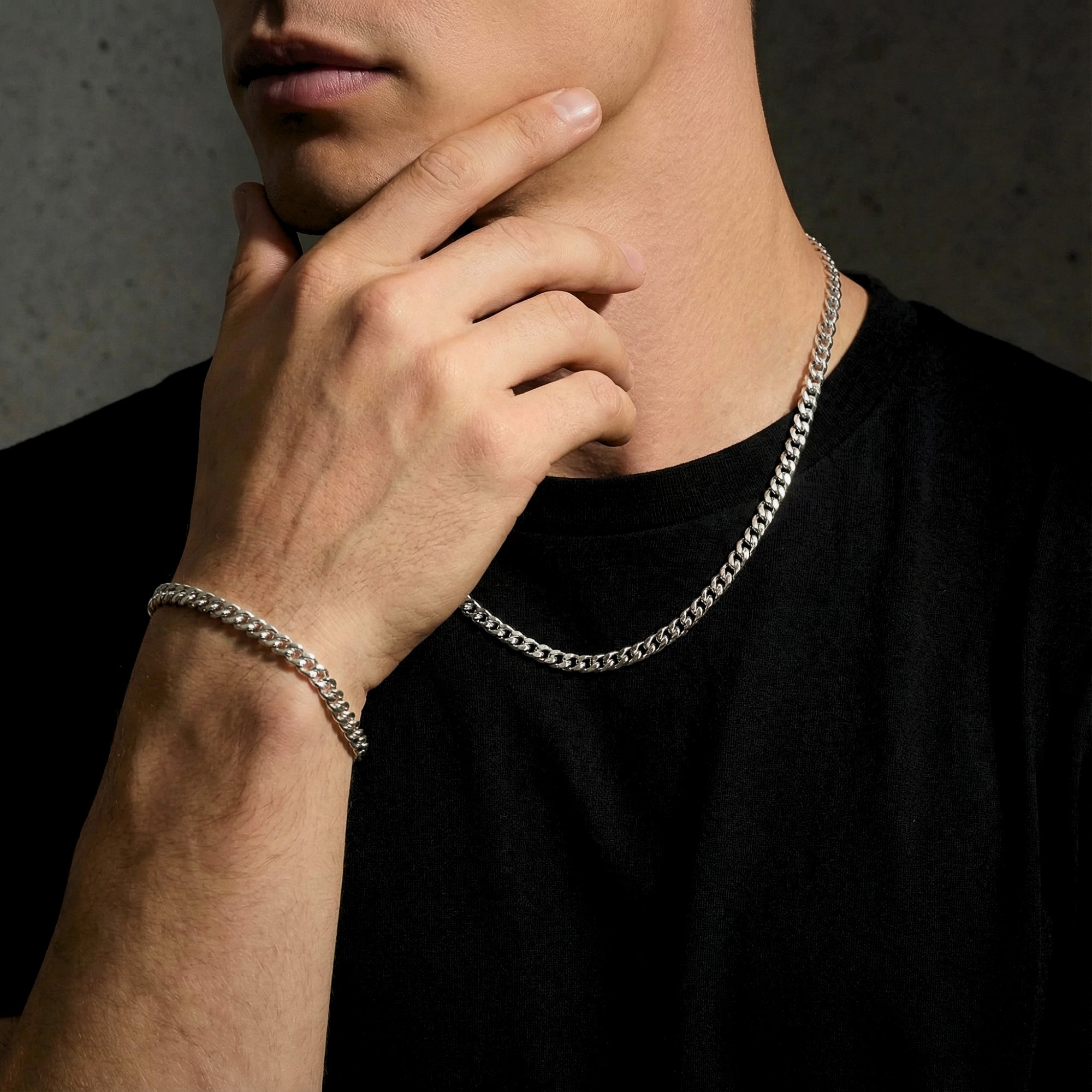 Male model wearing a 6mm silver stainless steel Cuban link chain and matching bracelet set.