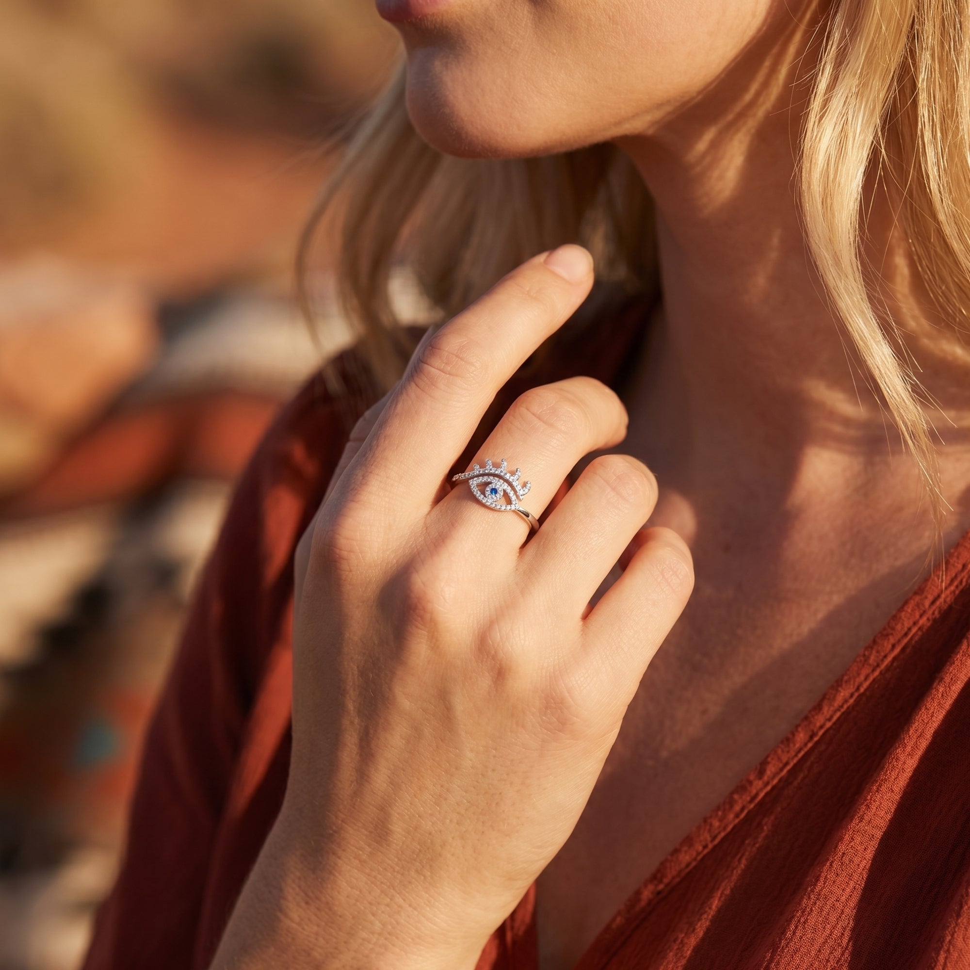 Woman wearing the sterling silver eye-shaped ring with clear accents and a blue center stone on her finger.
