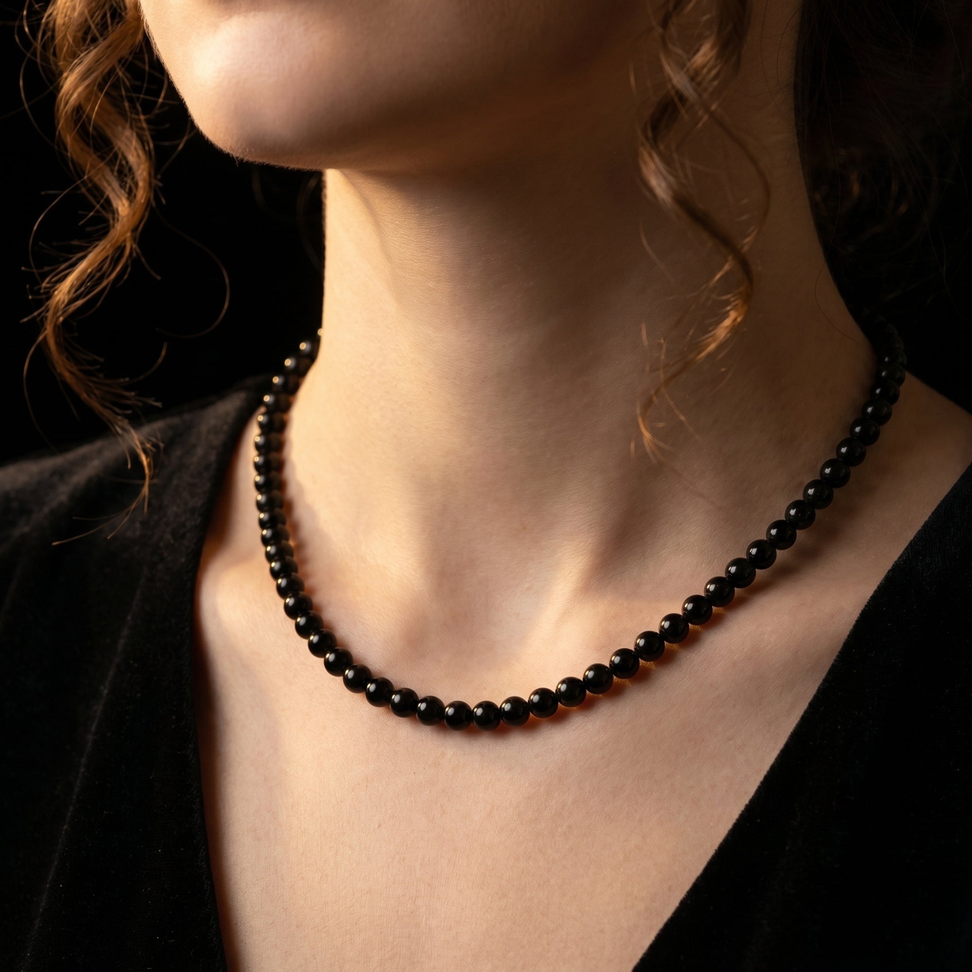 Close-up of a model wearing the 6mm round black onyx beaded necklace against a dark background.