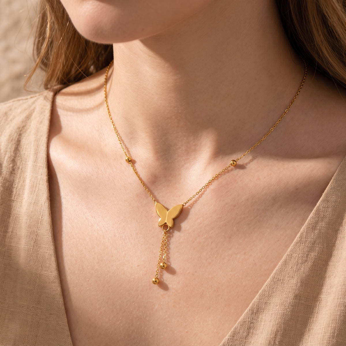 Close-up of a model wearing the gold-tone butterfly lariat necklace near her collarbone.