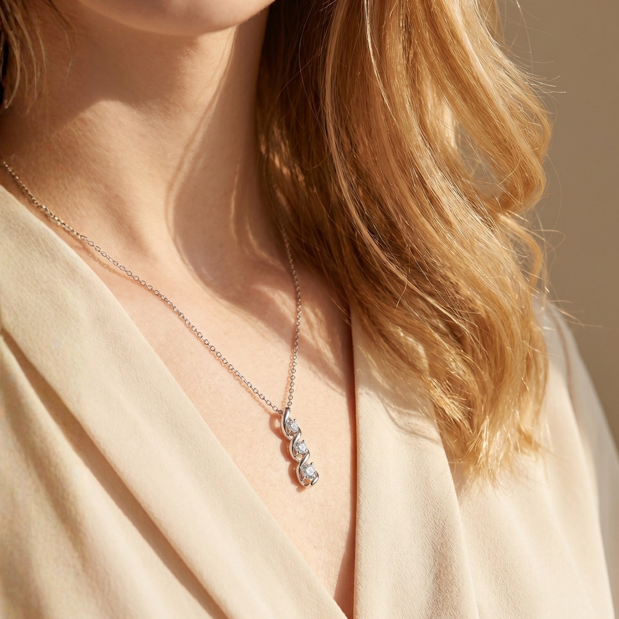 Woman wearing the silver Adrastia moissanite swirl pendant necklace against a neutral background.