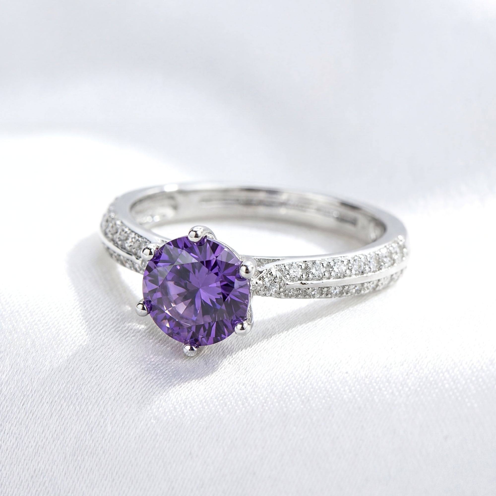 Macro view of a round-cut purple simulated amethyst in a sterling silver milgrain split-shank setting.