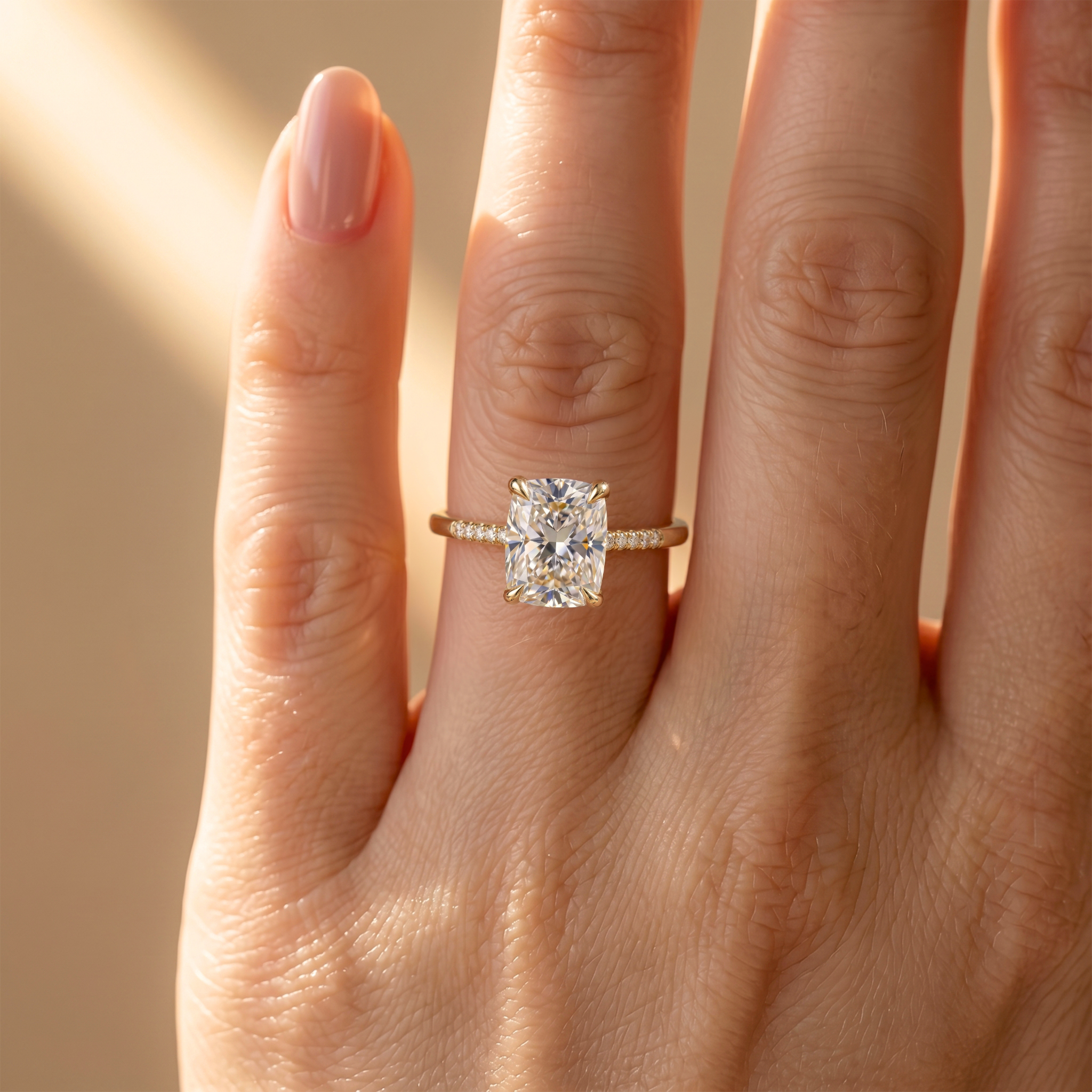 A yellow gold cushion-cut moissanite engagement ring with a pave-set band worn on a woman's ring finger.