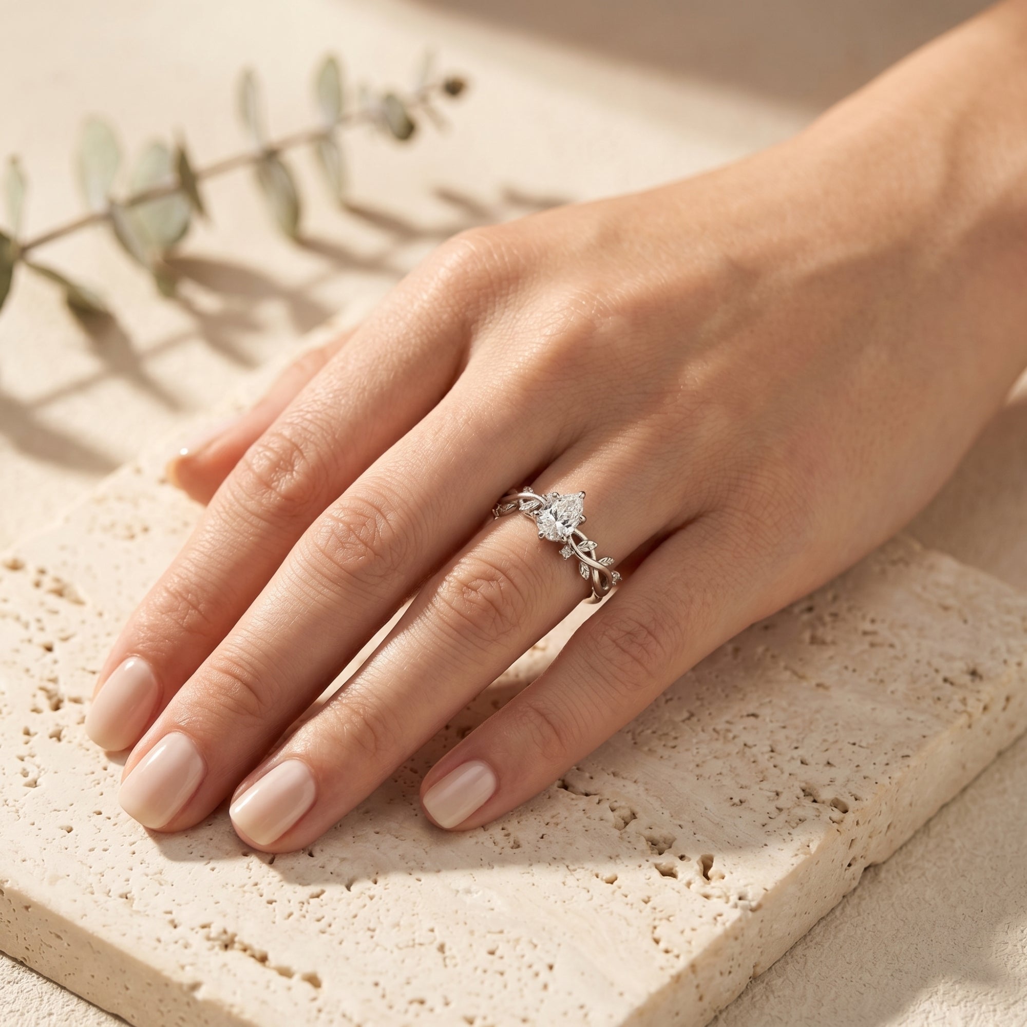 Silver pear cut moissanite promise ring worn on a woman's hand in a lifestyle setting.