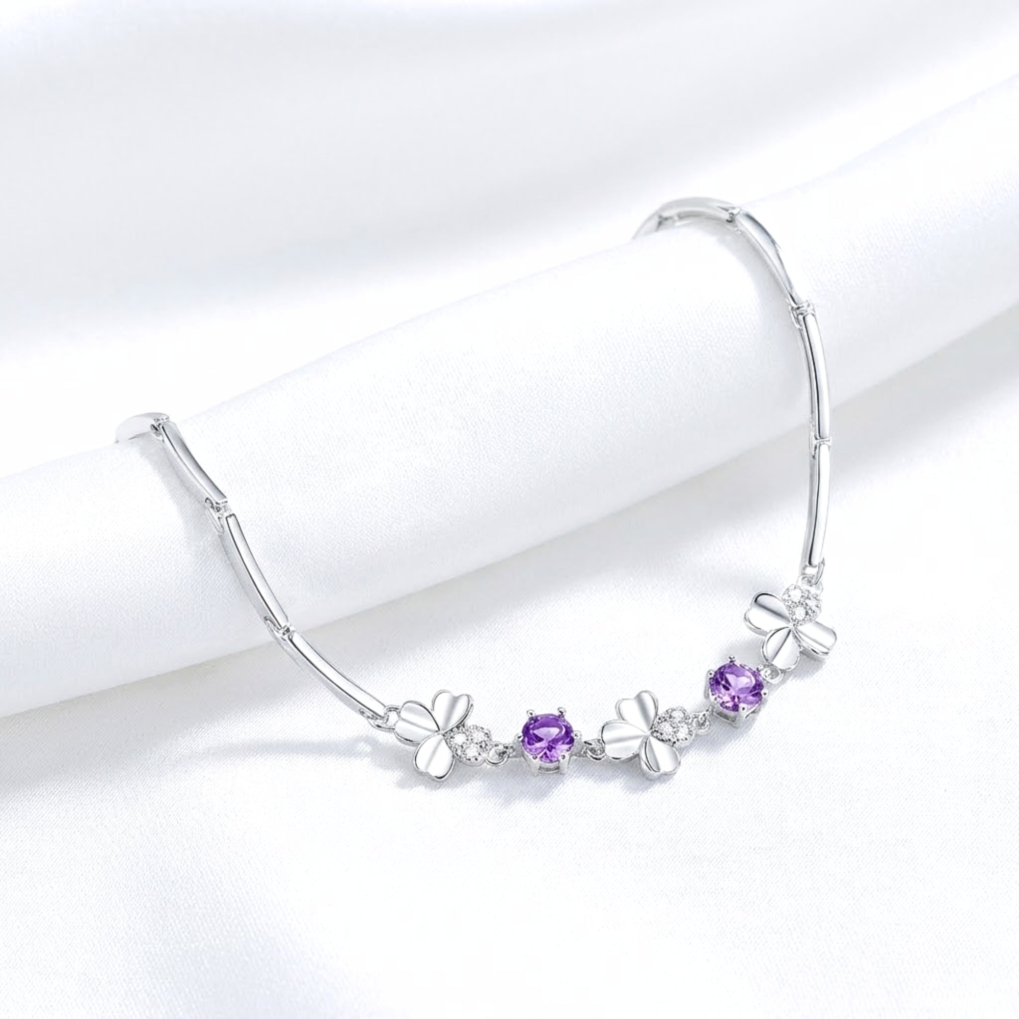 925 sterling silver clover bracelet with round purple simulated amethyst stones draped on white fabric.