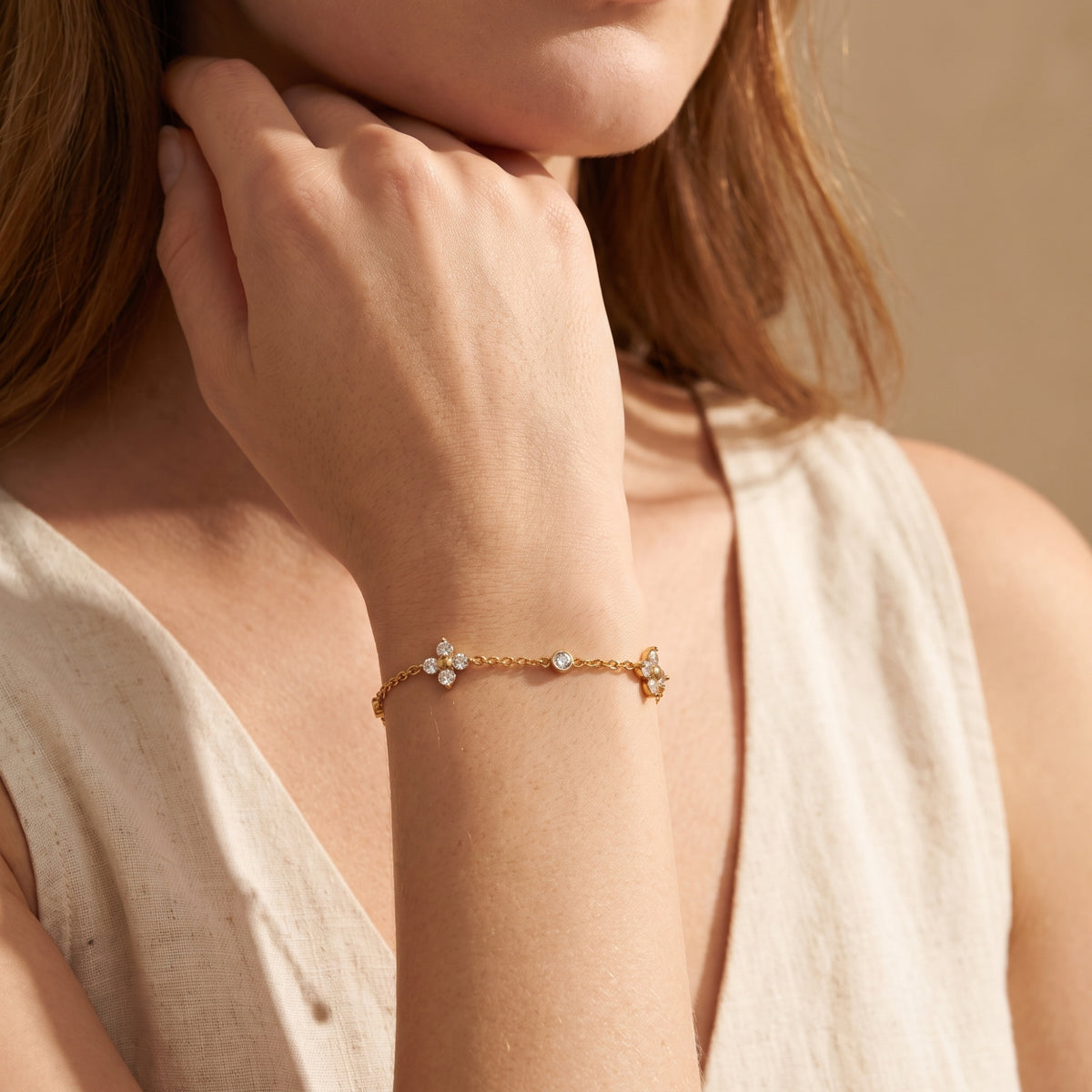 Model wearing the gold-tone Fleur Clover station bracelet on her wrist in a close-up lifestyle view.