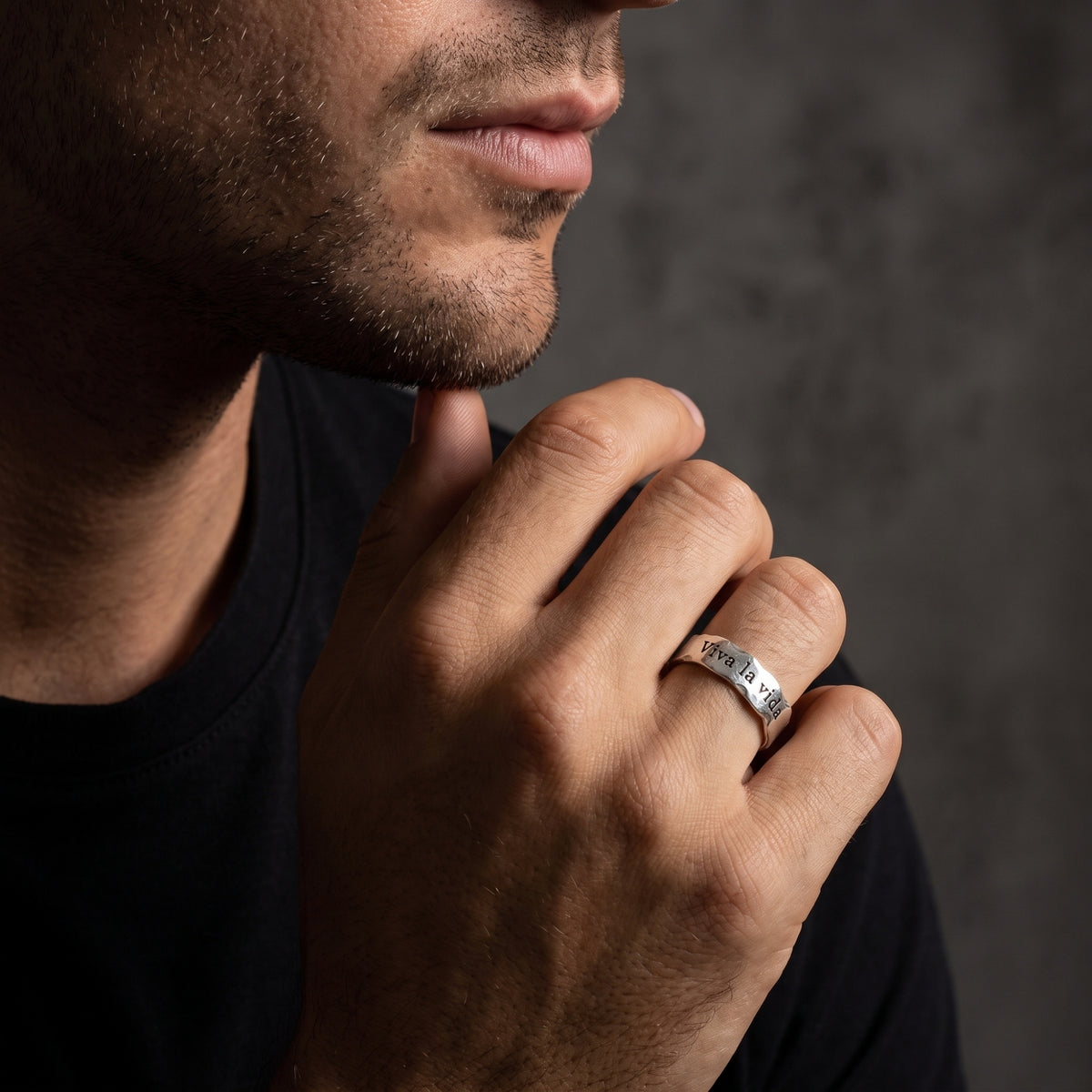 Close lifestyle view of a man touching his chin while wearing the textured silver Viva la vida ring.