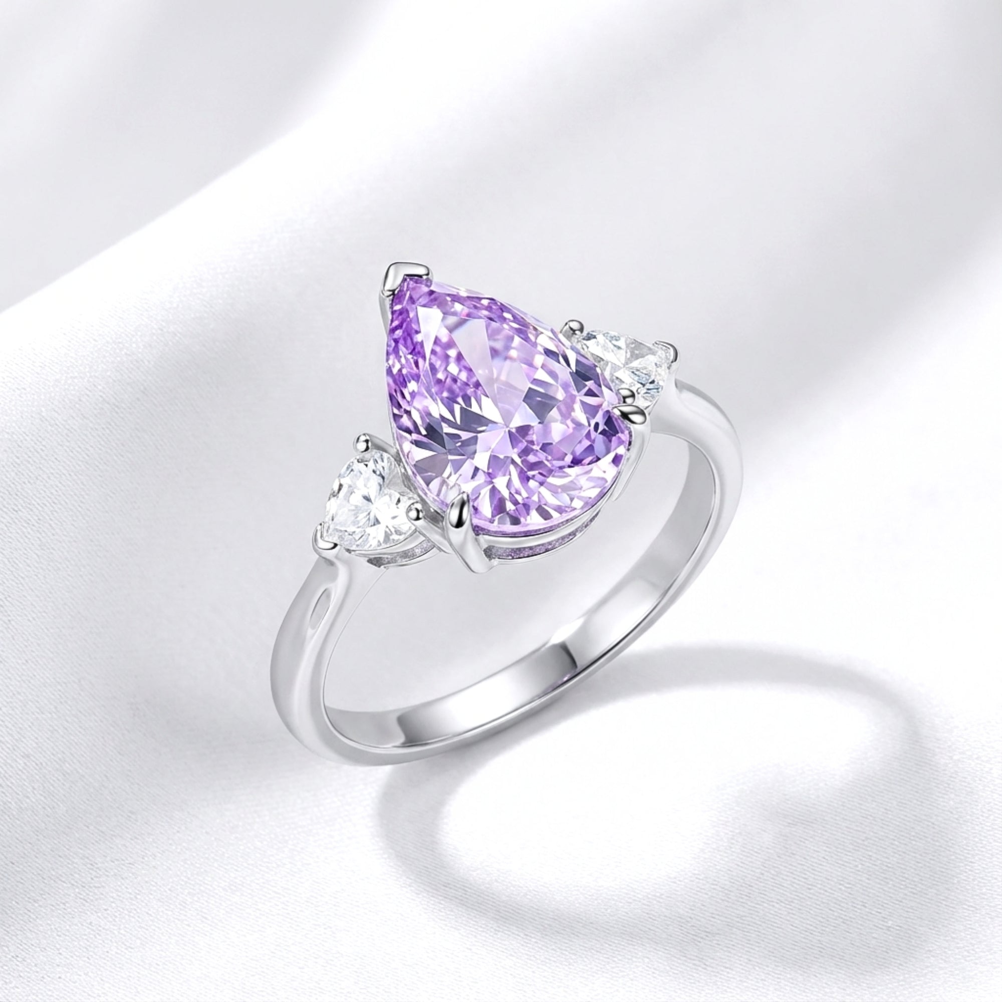 Pear-cut royal purple simulated amethyst ring in sterling silver on white silk, angled view.
