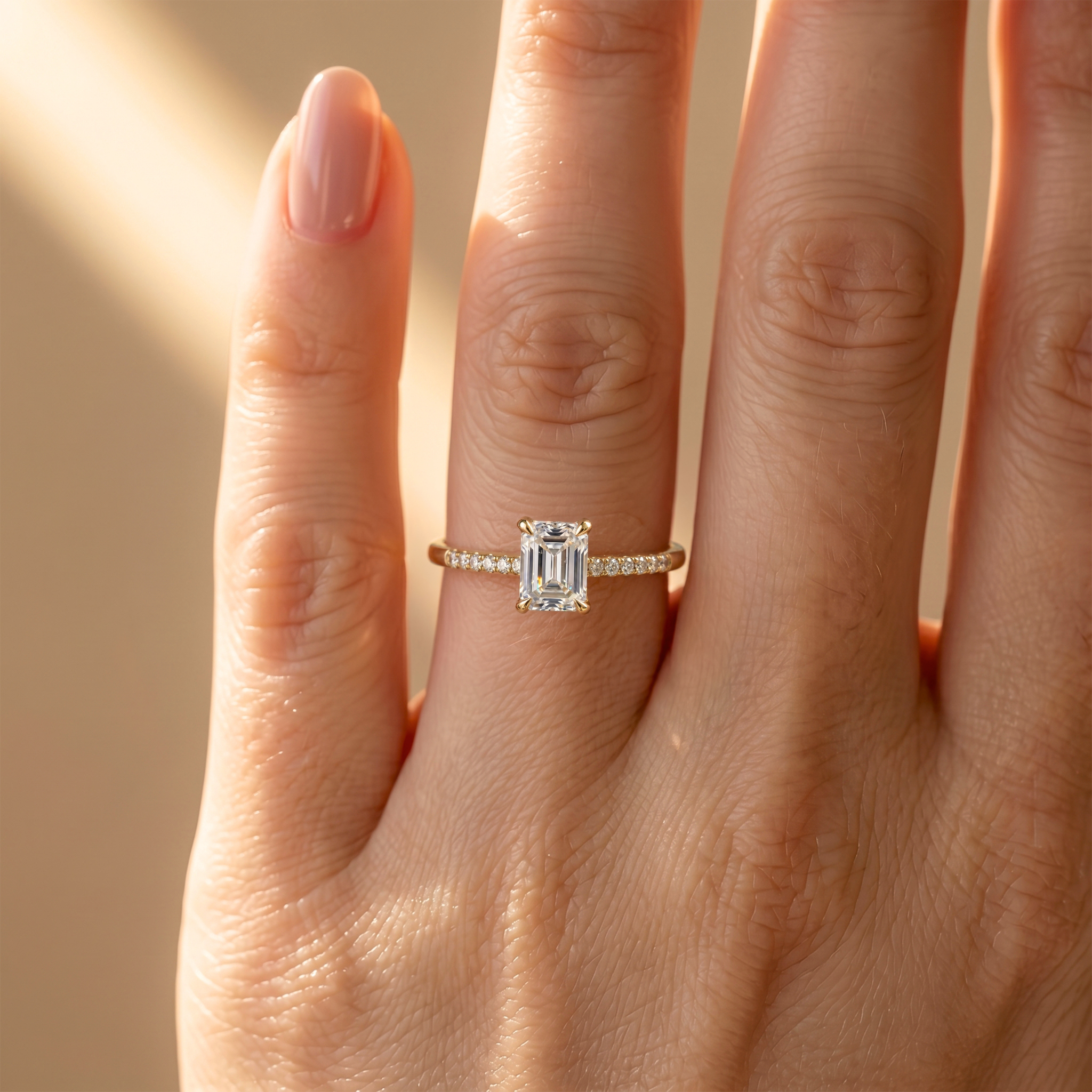A close-up view of the yellow gold emerald cut moissanite engagement ring worn on a finger.