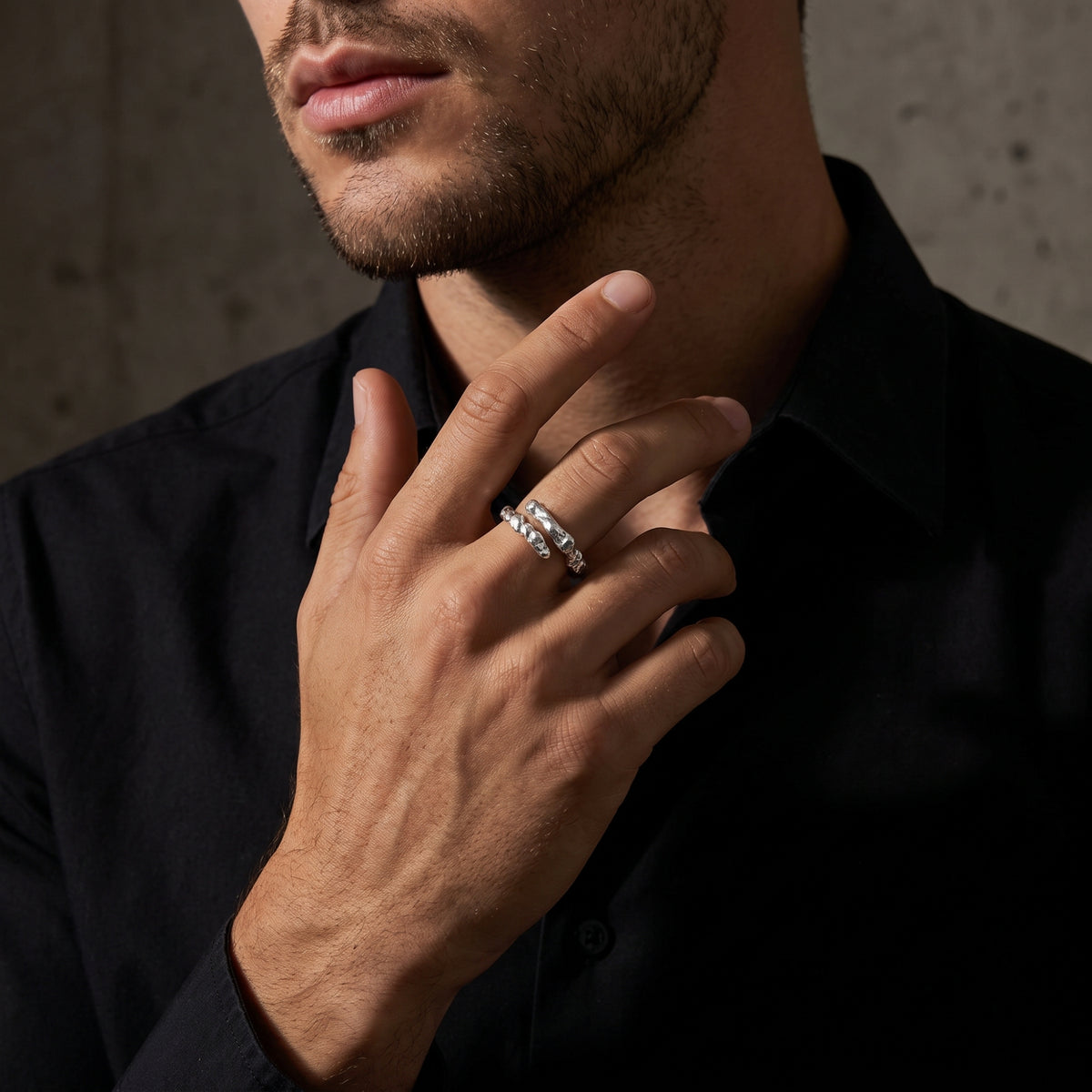 Model wearing the silver molten wrap ring on his middle finger against a black shirt.