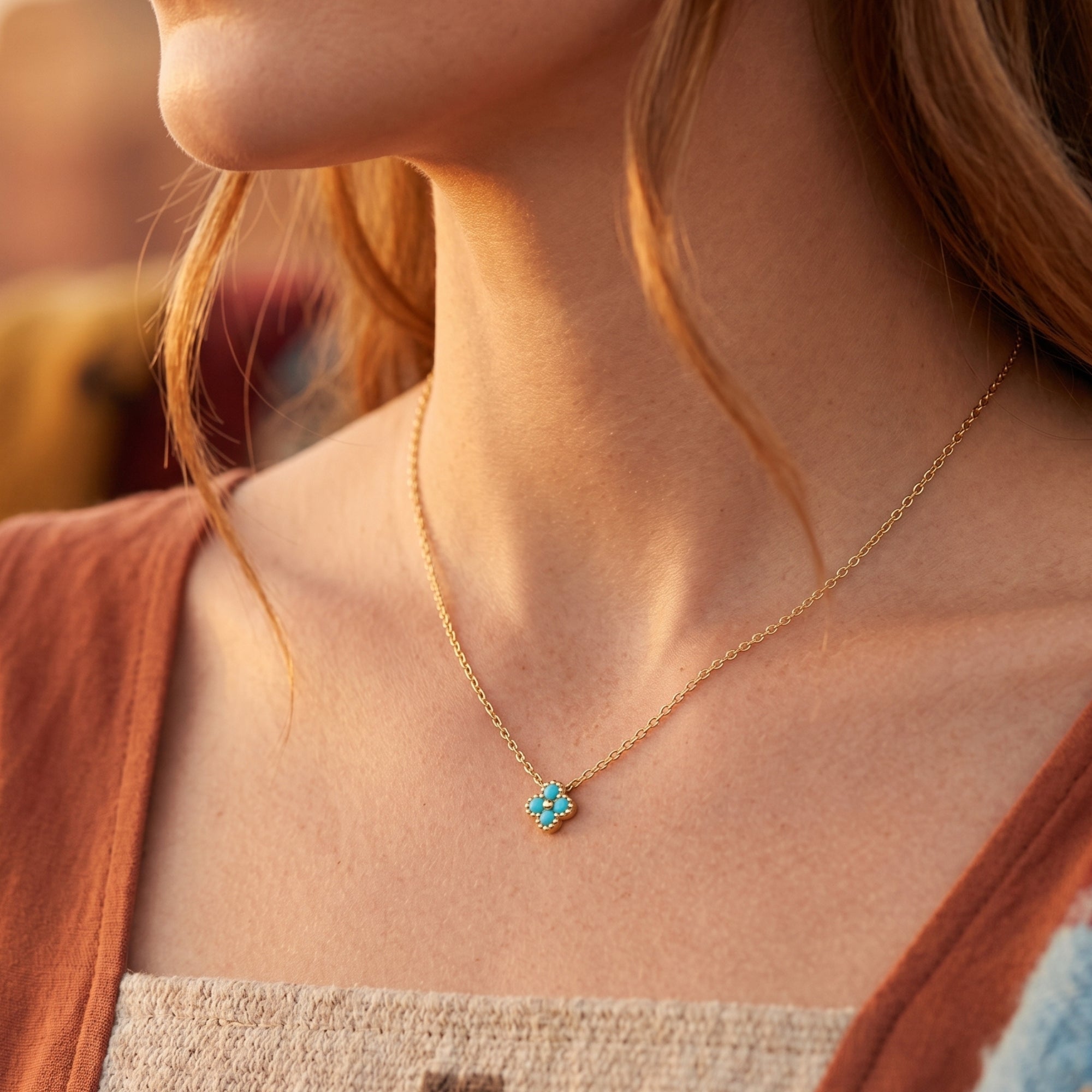 Woman wearing the gold Sonoran turquoise flower necklace against a warm, sunlit background.