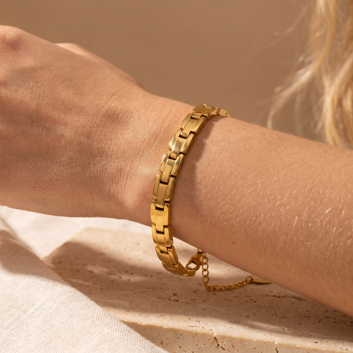 Gold-tone sculpted link bracelet worn on a wrist, showcasing its thick interlocked link structure.