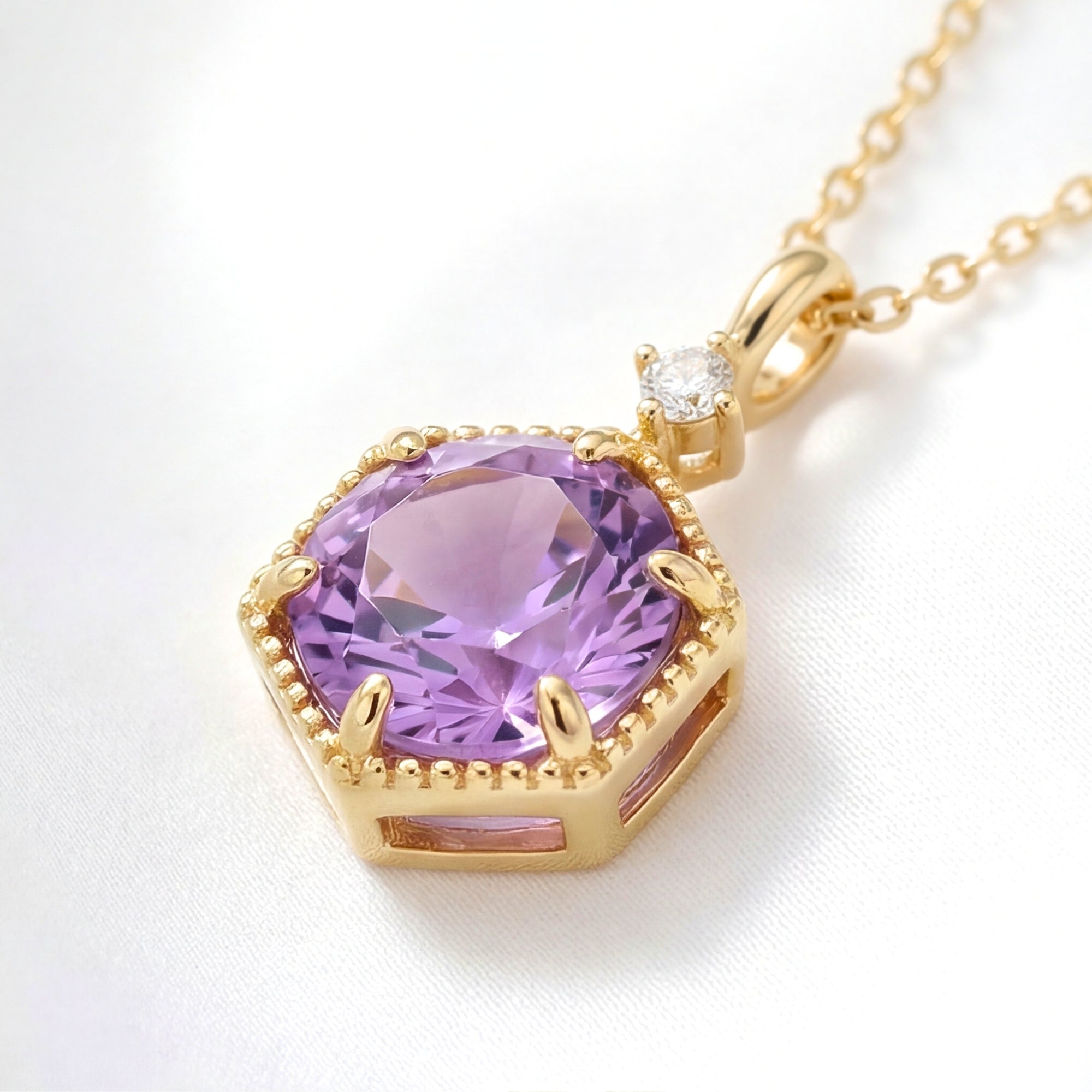 Angled detail shot of the Hesperia necklace showing the gold vermeil hexagon setting and purple amethyst stone.